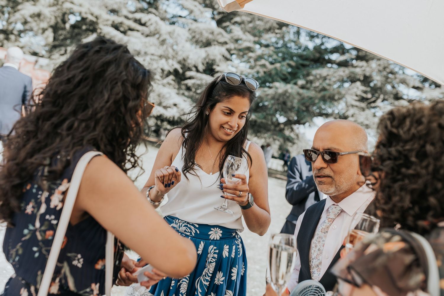 Guests socializing at an outdoor wedding reception, holding champagne glasses amid a festive atmosphere.