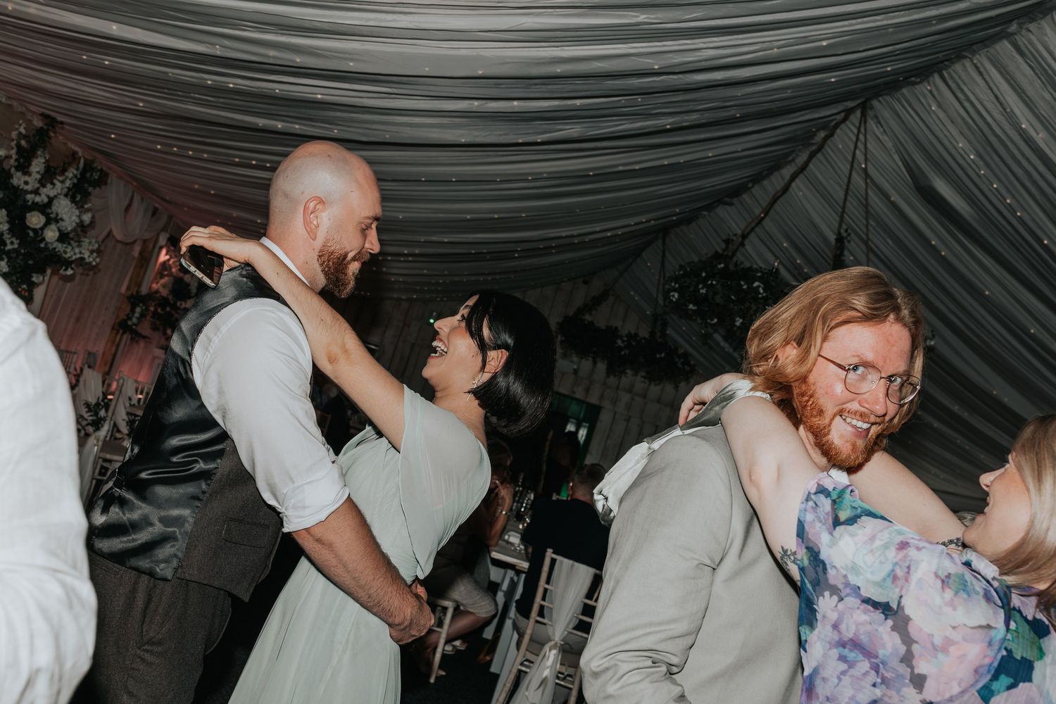 Couple sharing a romantic dance at a wedding reception in a decorated marquee venue.
