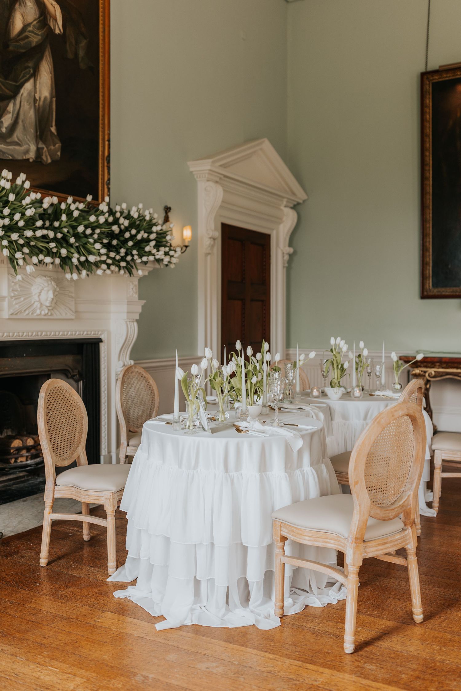 A formal dining room with a white tablecloth, floral centerpiece, and ornate chairs arranged around the table.