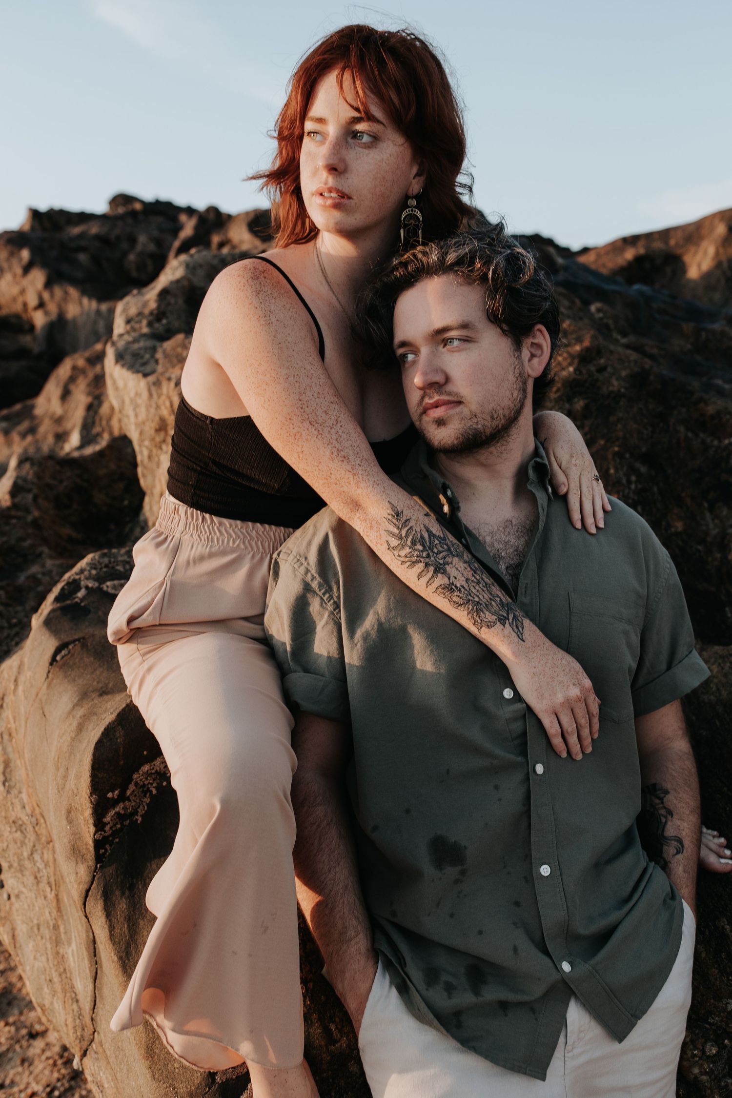 A couple embracing in a rugged, mountainous landscape at sunset in Porto