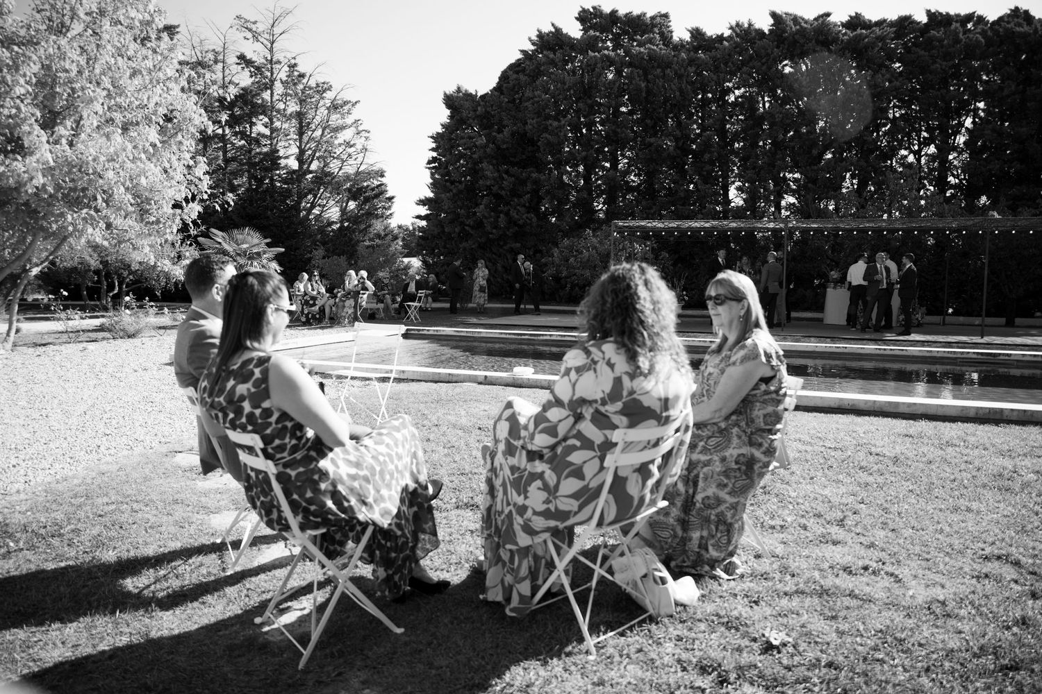 Three people sitting in chairs on a grassy lawn with trees in the background in South Of France