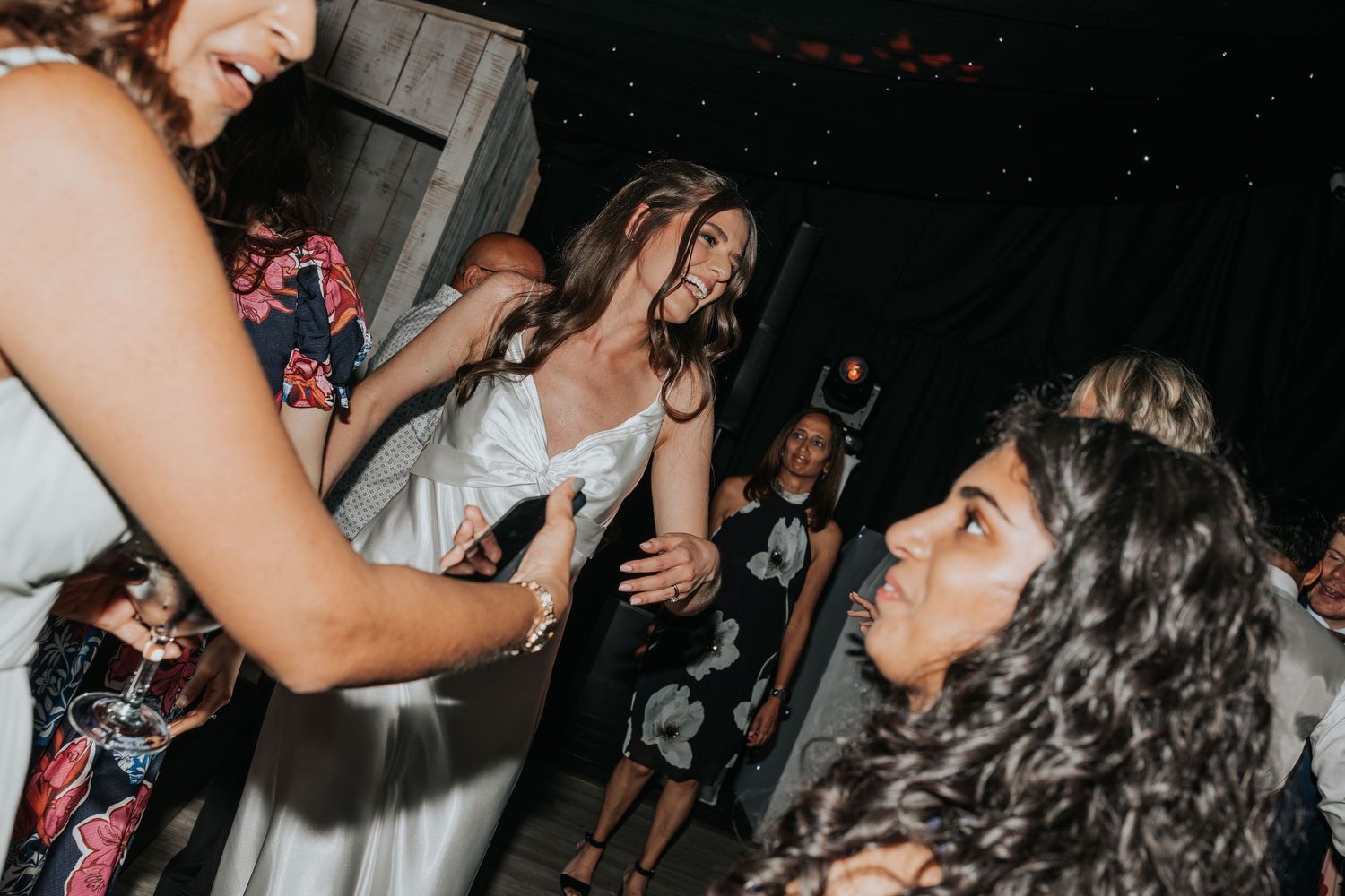 Guests dancing and laughing together at a lively wedding reception party on the dance floor.