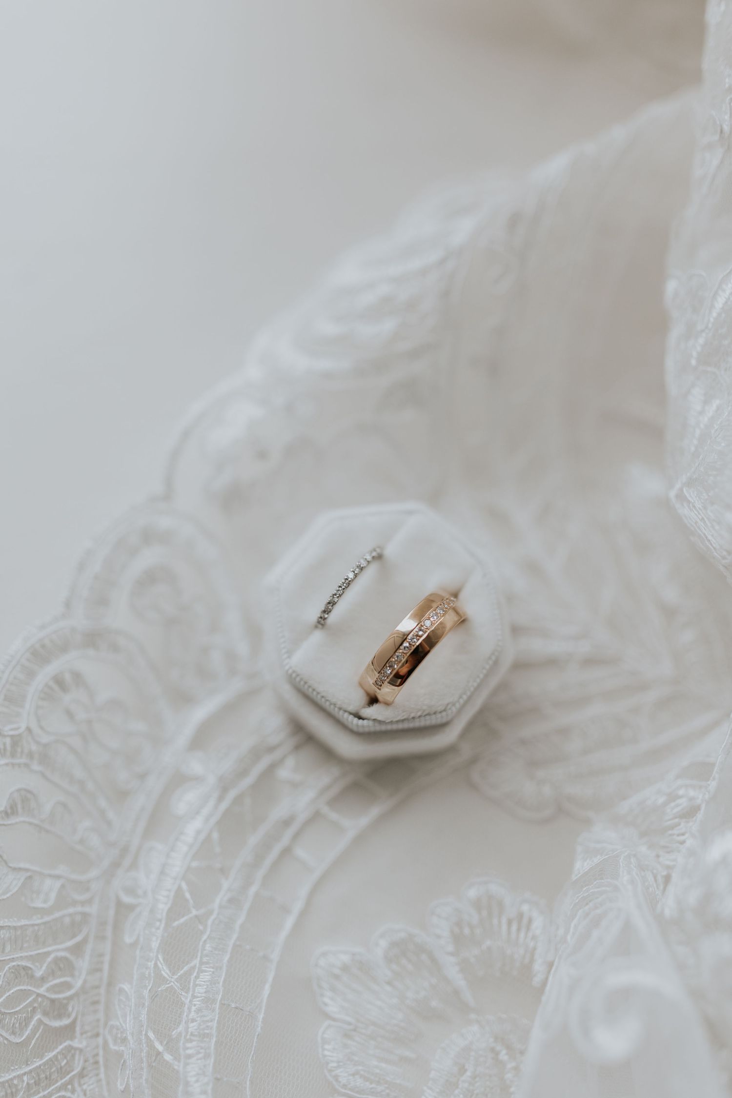 The image shows a close-up of a white lace fabric with a gold ring resting on it.