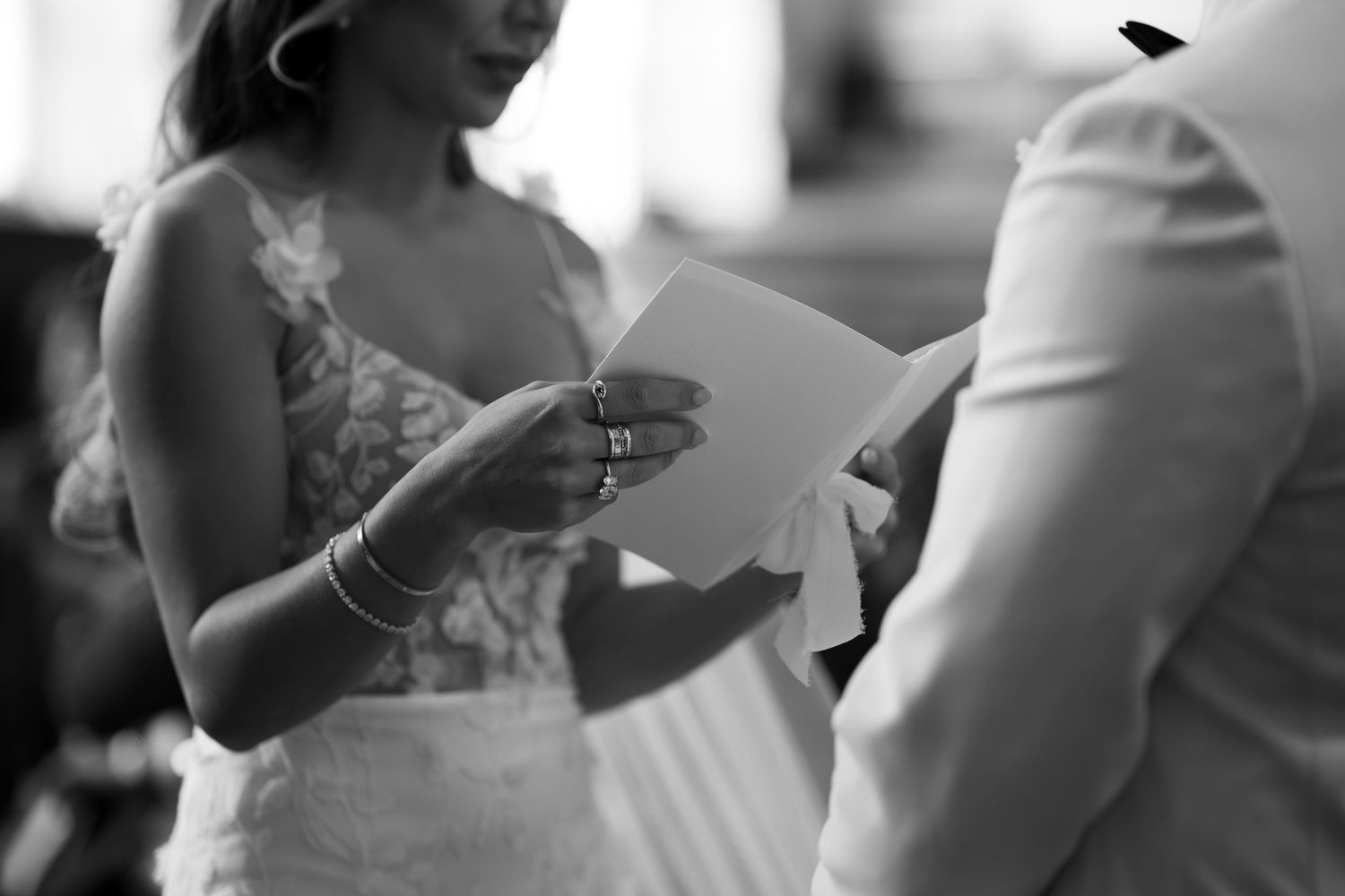A black and white image of a bride and groom exchanging wedding vows or documents during their wedding ceremony.