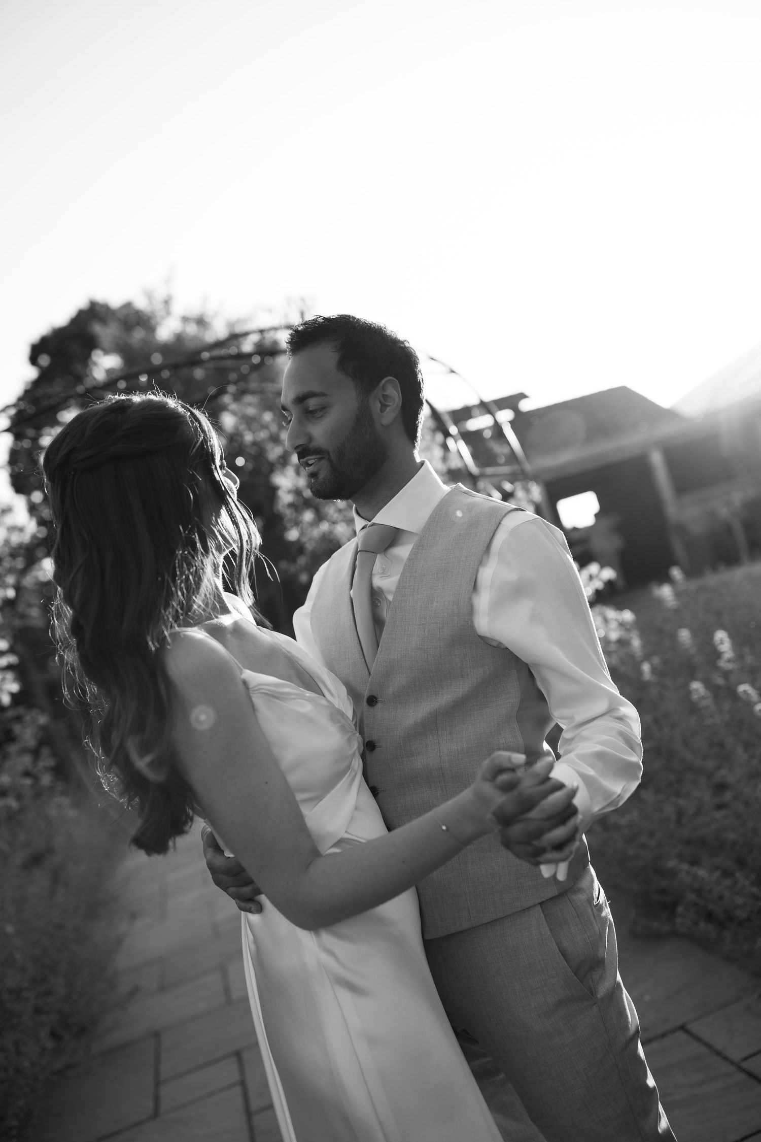 Black and white photo of a bride and groom sharing a romantic dance outdoors on their wedding day.