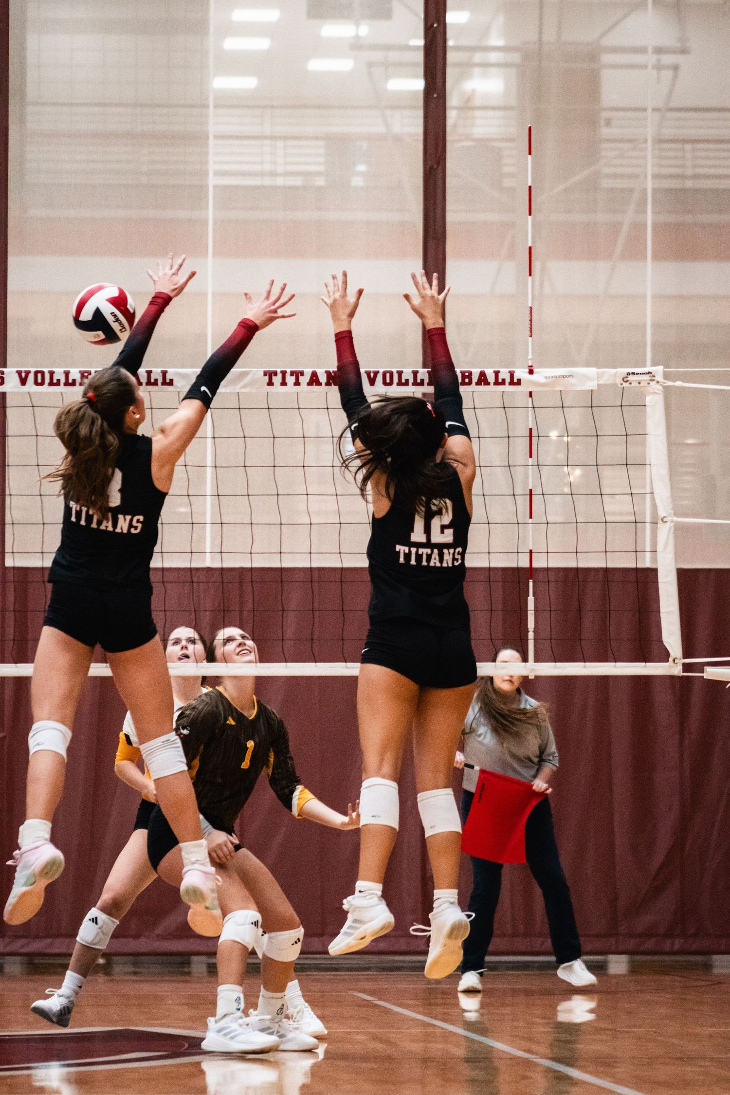 IUSB volleyball players competing at the net during an indoor college volleyball match.