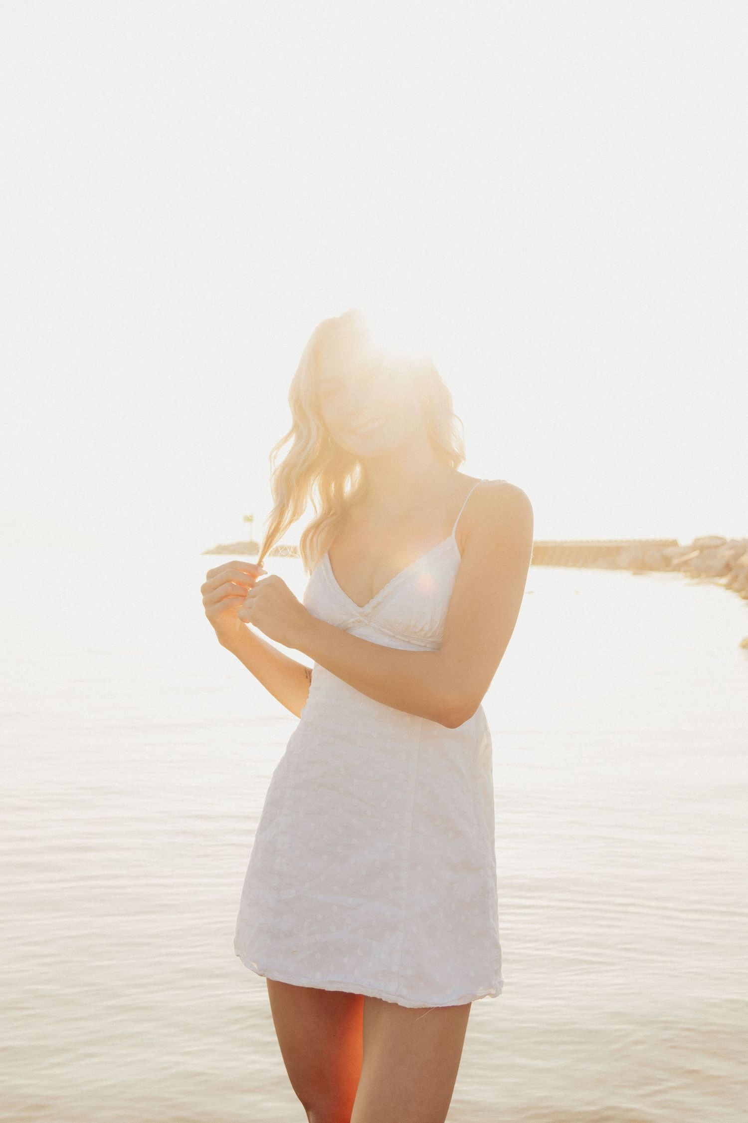Senior portrait of Arabella Churchill standing by the water at sunset
