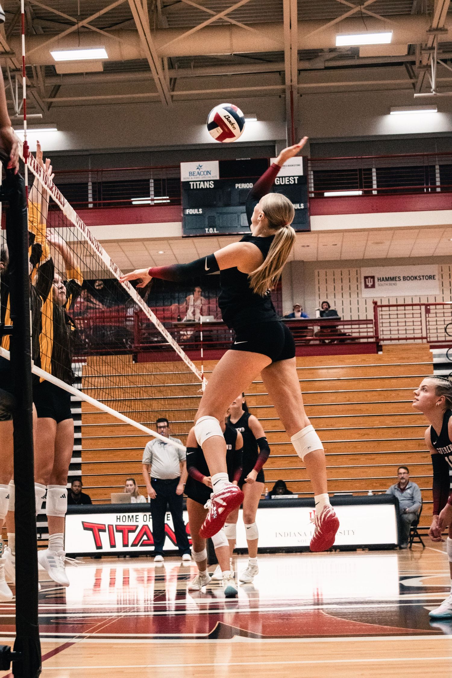 IUSB volleyball player jumping at the net during an indoor college volleyball match.