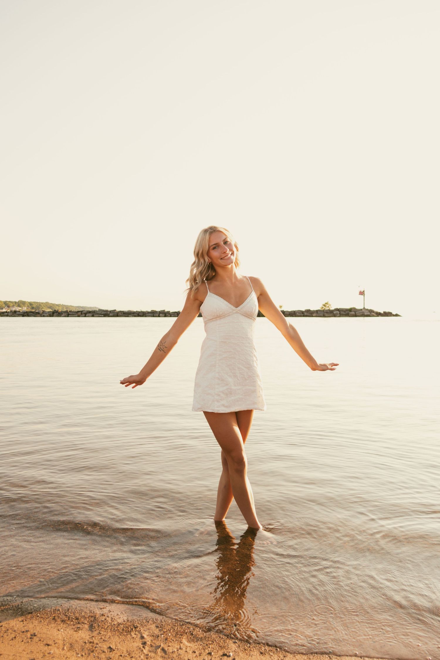 Senior portrait of Arabella Churchill standing by the water at sunset