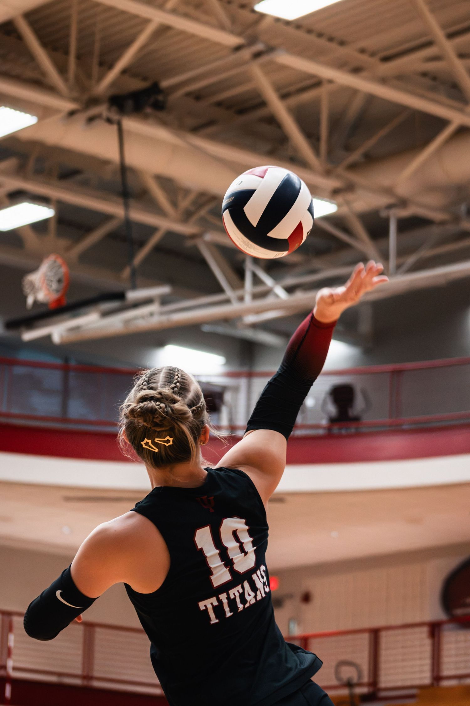 IUSB volleyball player jumping to attack the ball above the net during a college match.