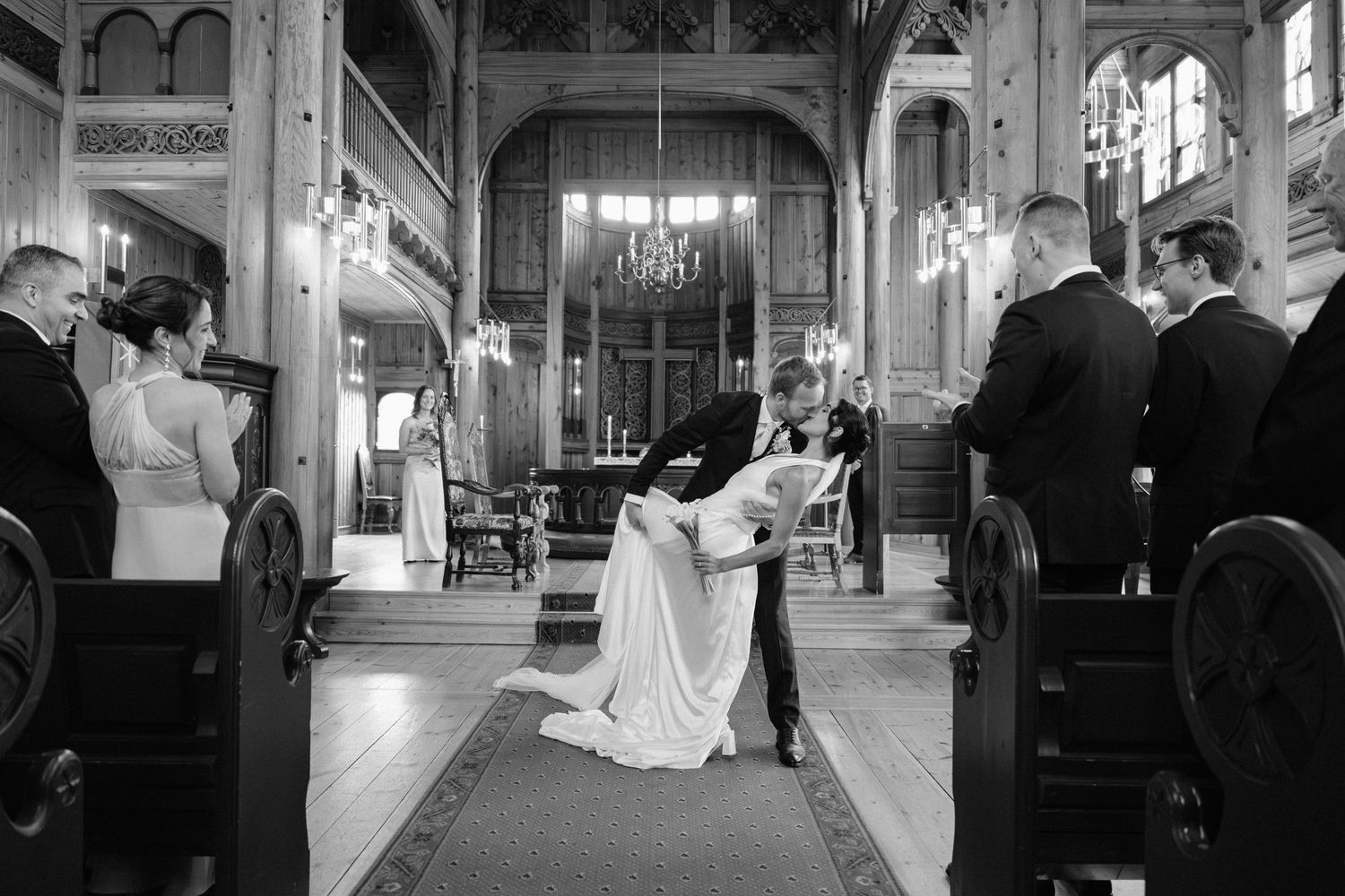 Bride and groom share a romantic kiss during their wedding ceremony in an elegant church aisle.