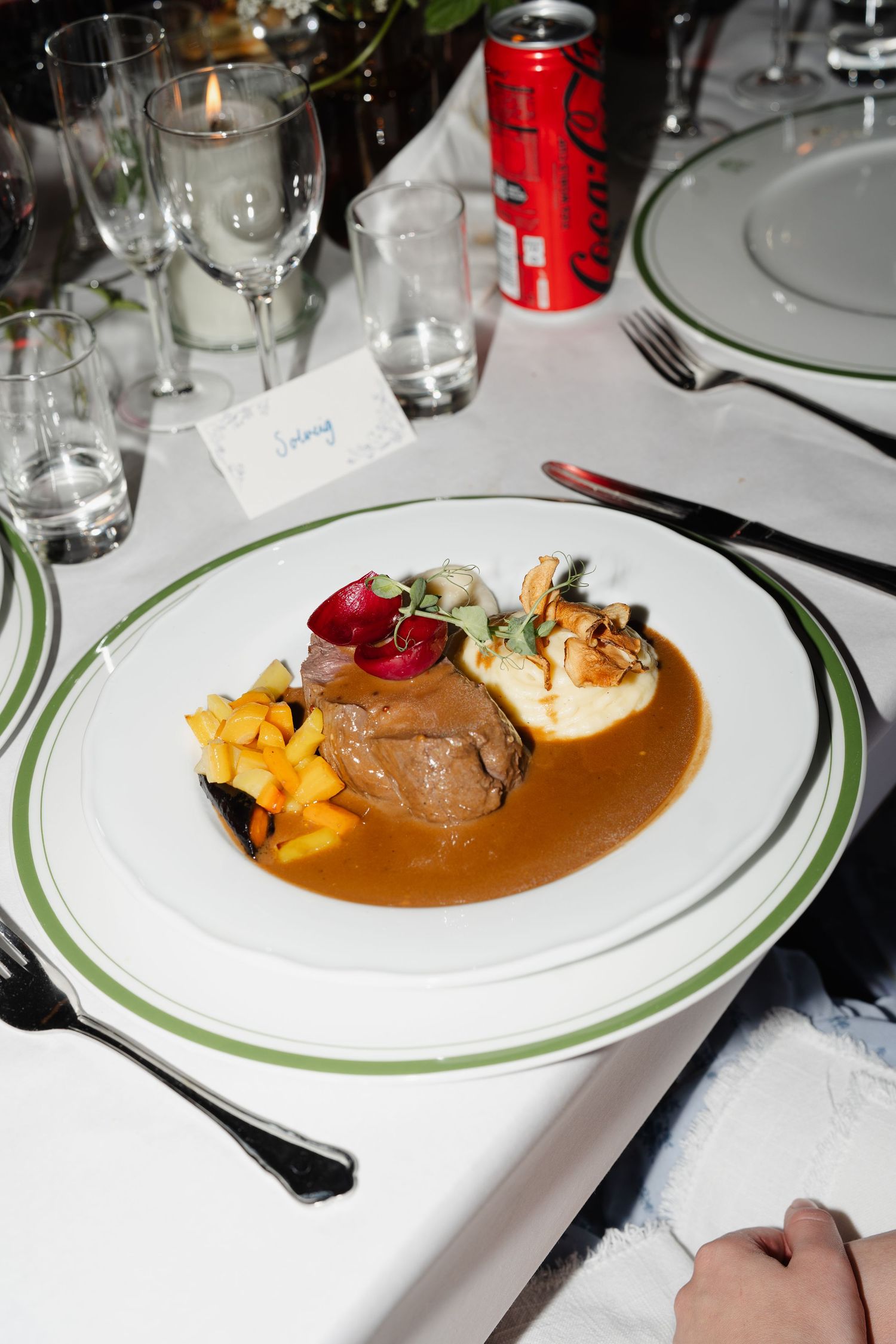 Elegant wedding reception dinner plate with braised meat, gravy, and garnishes.