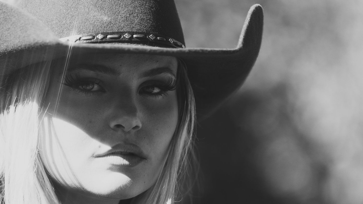 Black and white portrait of a blonde woman in a cowboy hat with a serious expression.