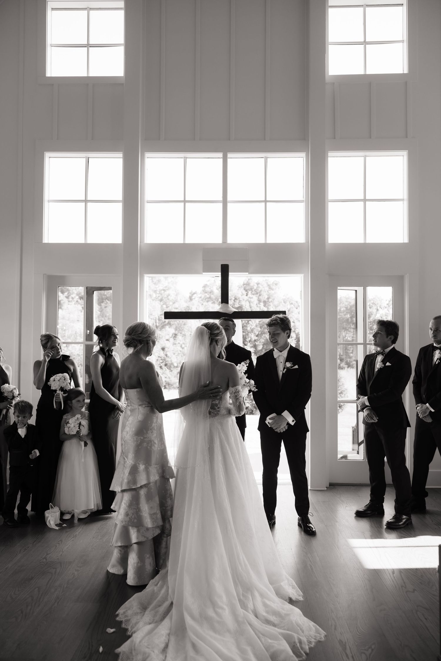 Black and white photo of bride and groom at altar during indoor wedding ceremony.