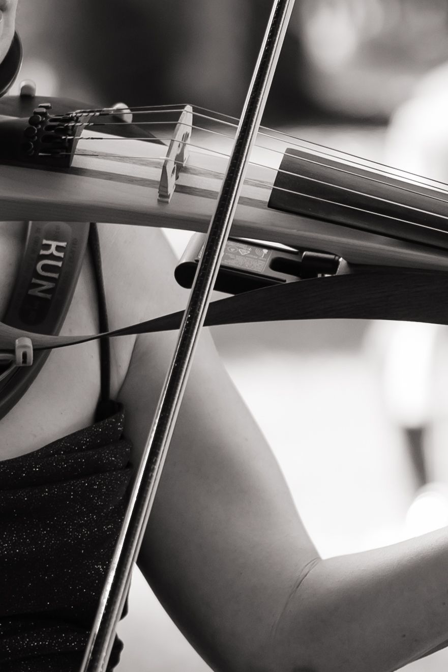 Close-up black and white photo of a violin being played with a bow during a musical performance.