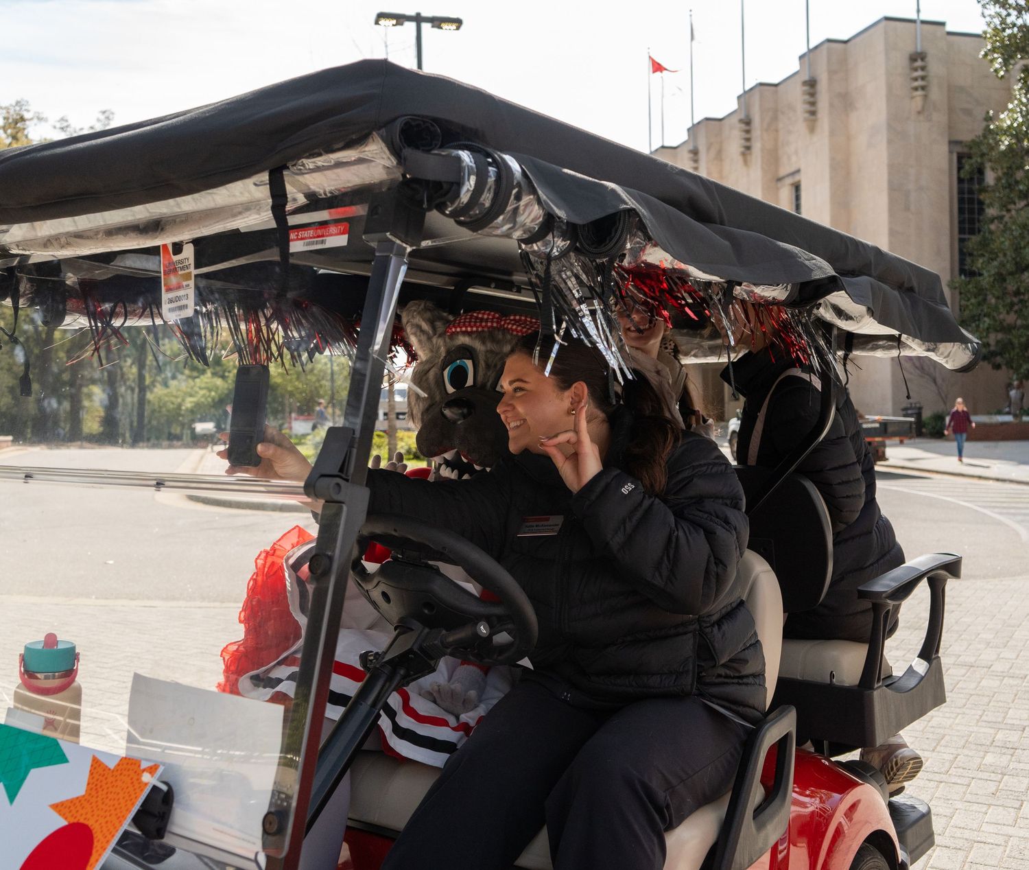 Woman in black outfit sits relaxed on decorated golf cart in urban plaza setting.