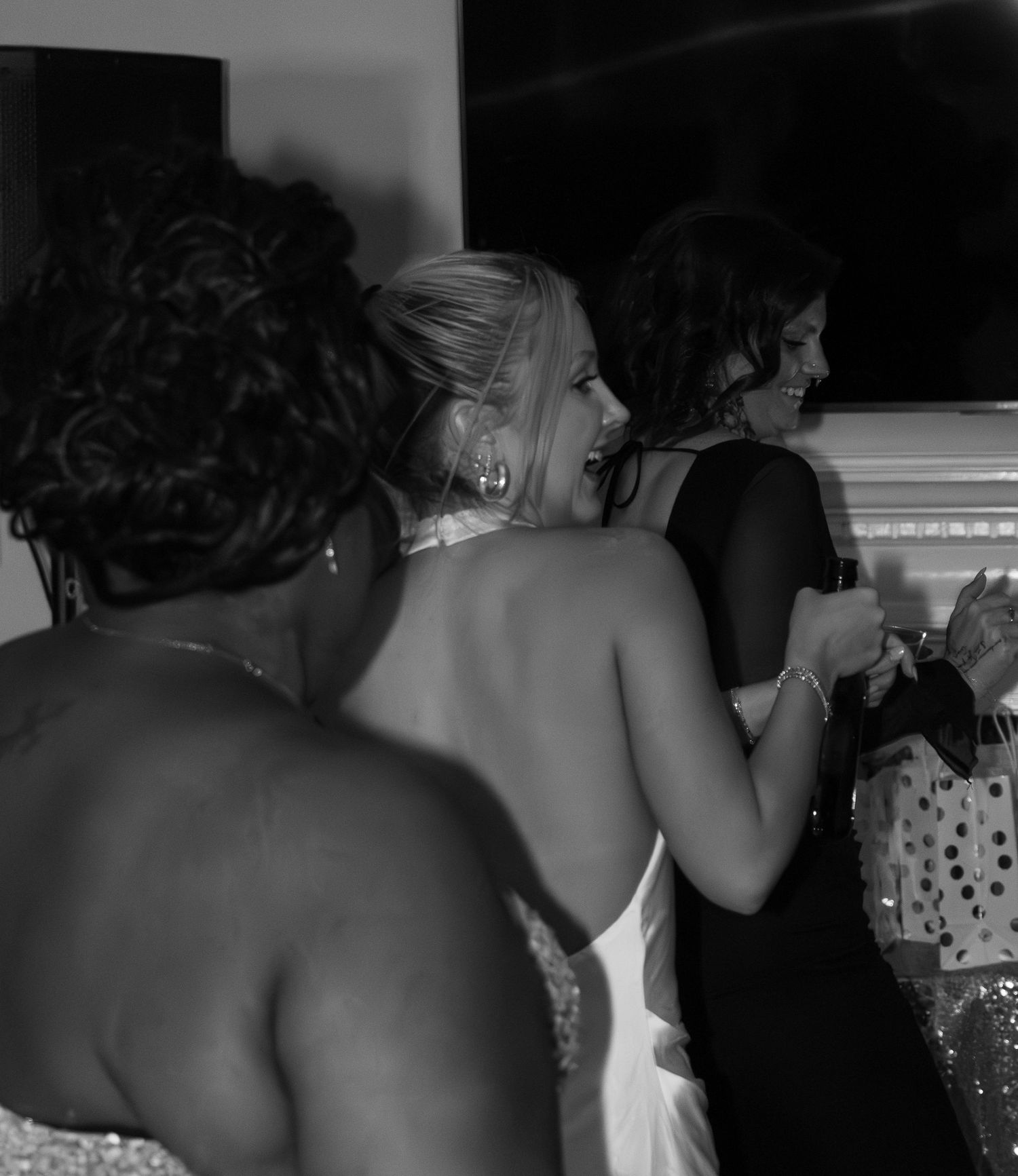 Black and white photo of elegantly dressed women socializing at an indoor event.