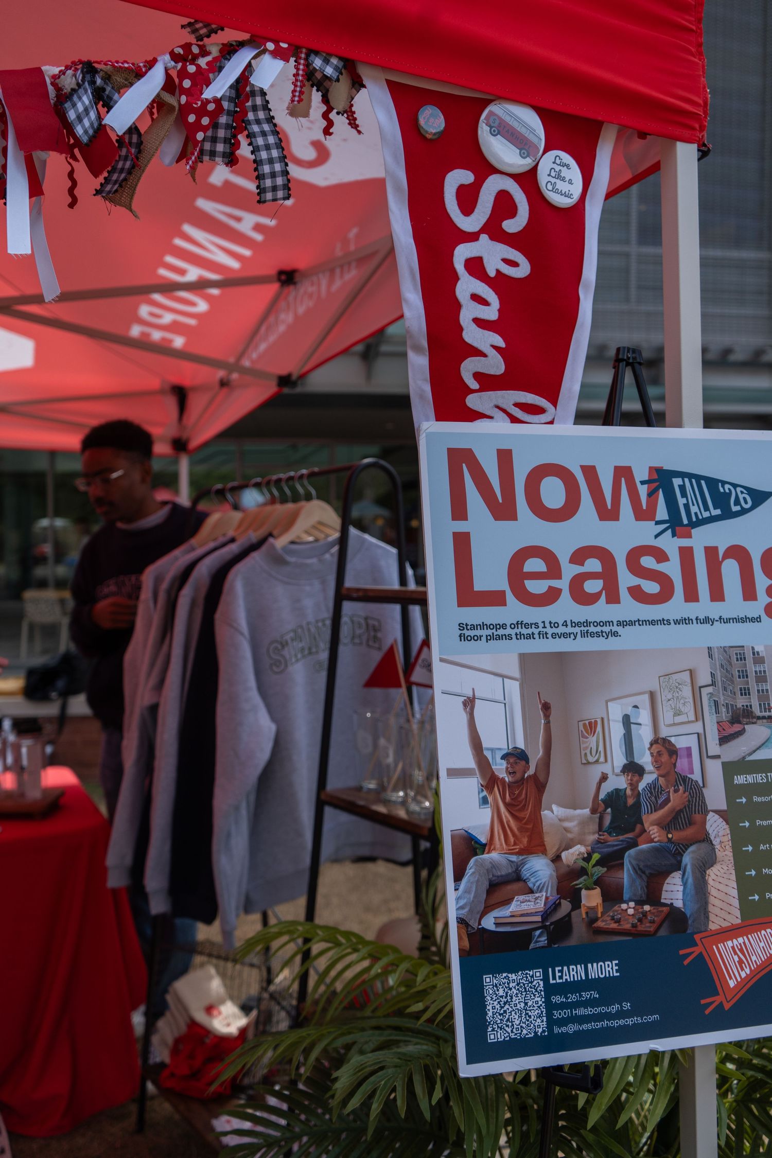 A Now Leasing sign for Stanhope apartments displayed at an outdoor college event booth.