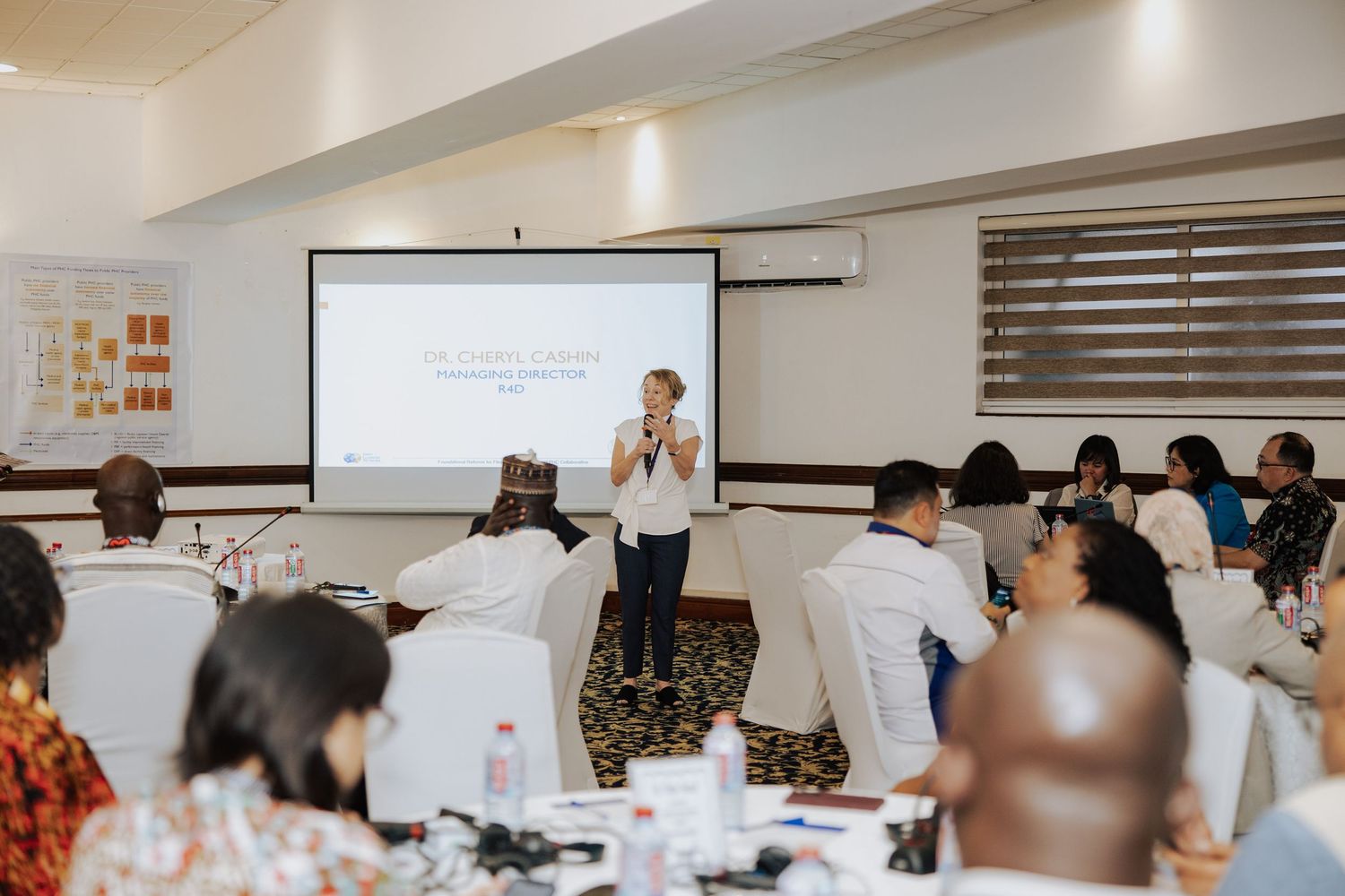 Presenter delivering a workshop to a diverse group of attendees in a bright conference room.