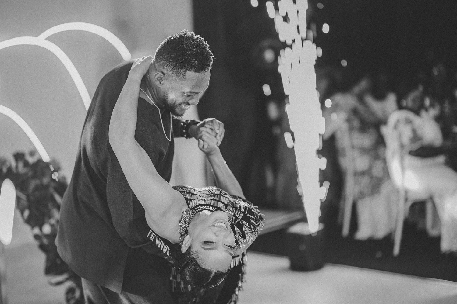 Black and white romantic wedding first dance photo with couple dipping amid sparkling fireworks.