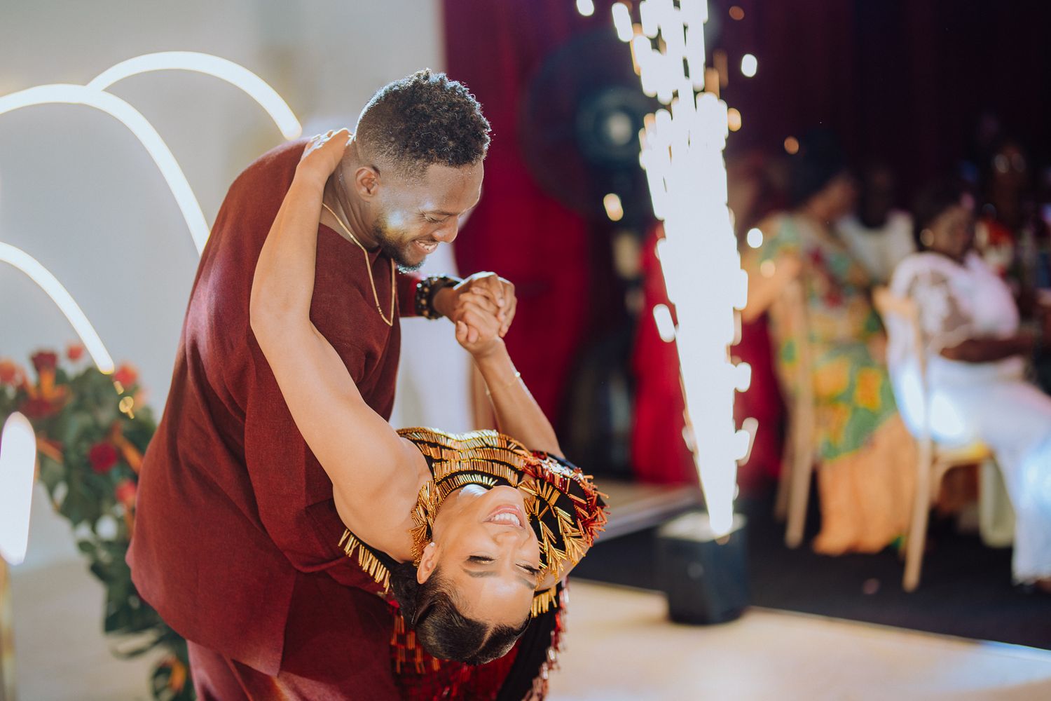 A couple performs a dramatic first dance dip with sparkling pyrotechnics at their wedding reception.