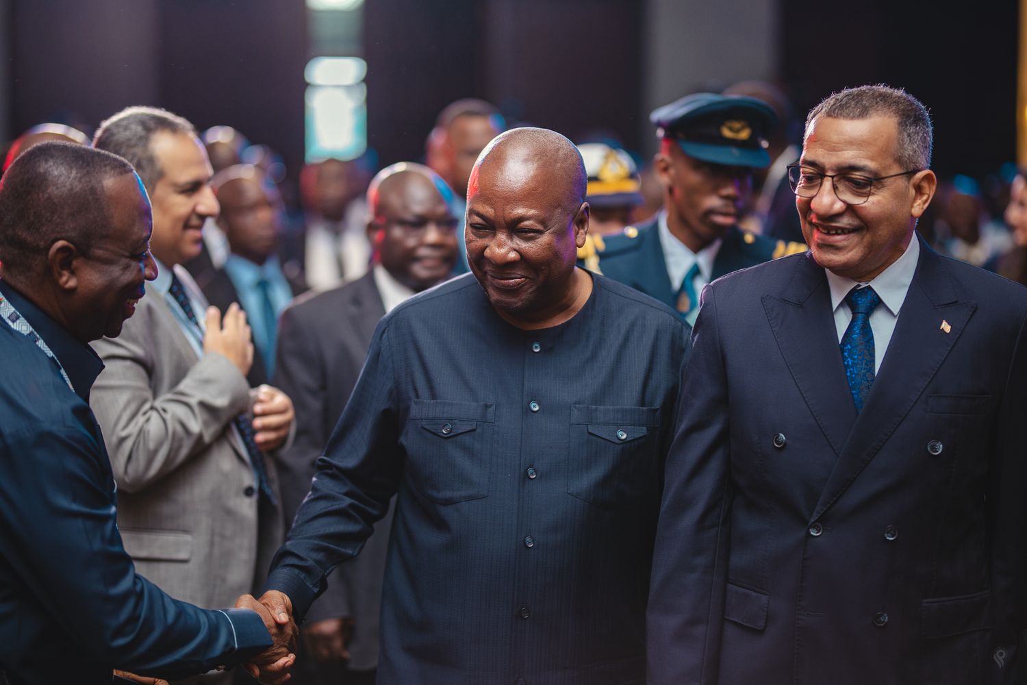 African dignitaries in formal attire sharing a warm greeting at an official government event.
