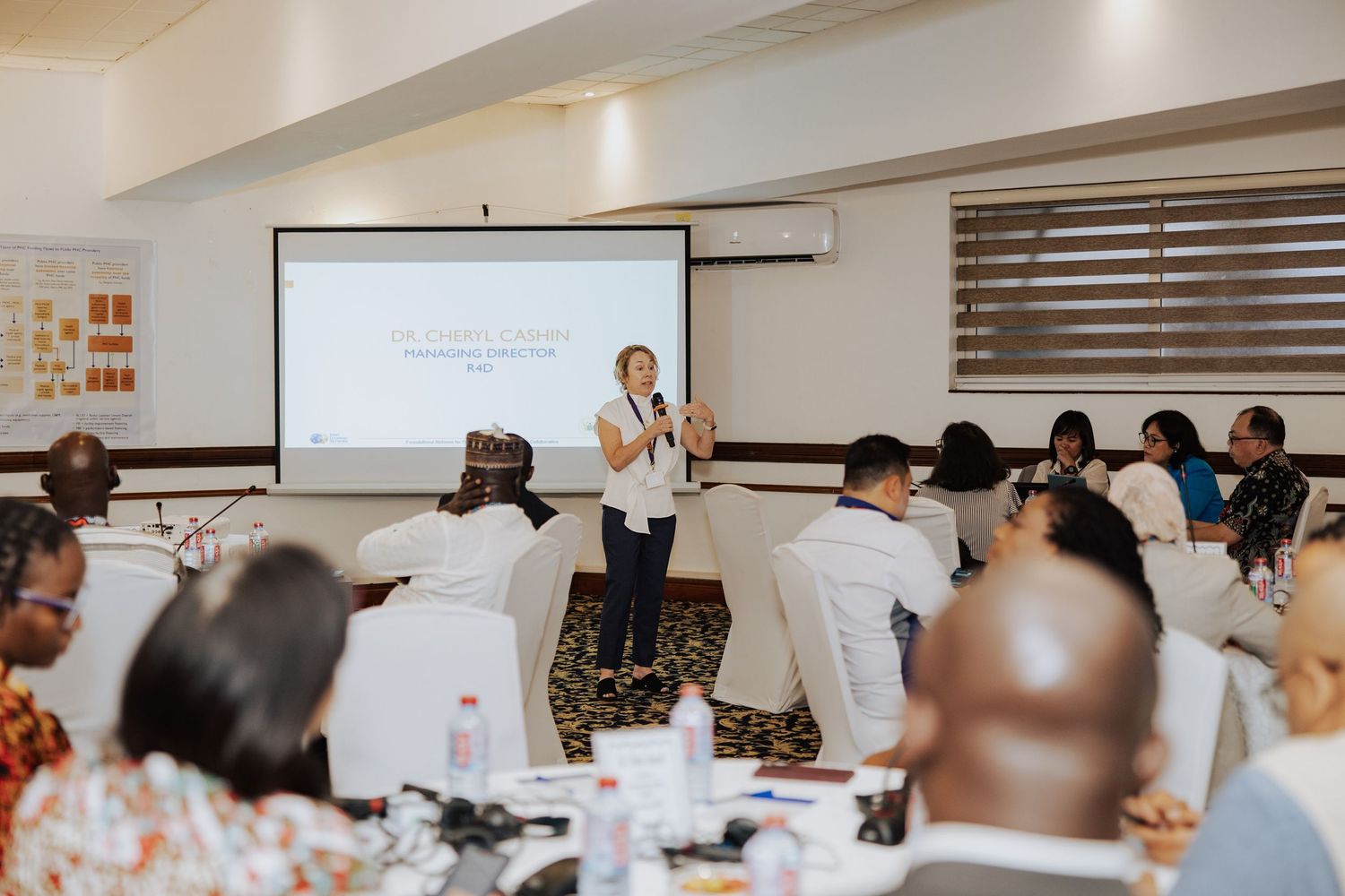 Professional presenter delivering a business seminar to a diverse audience in a modern conference room with projector screen.