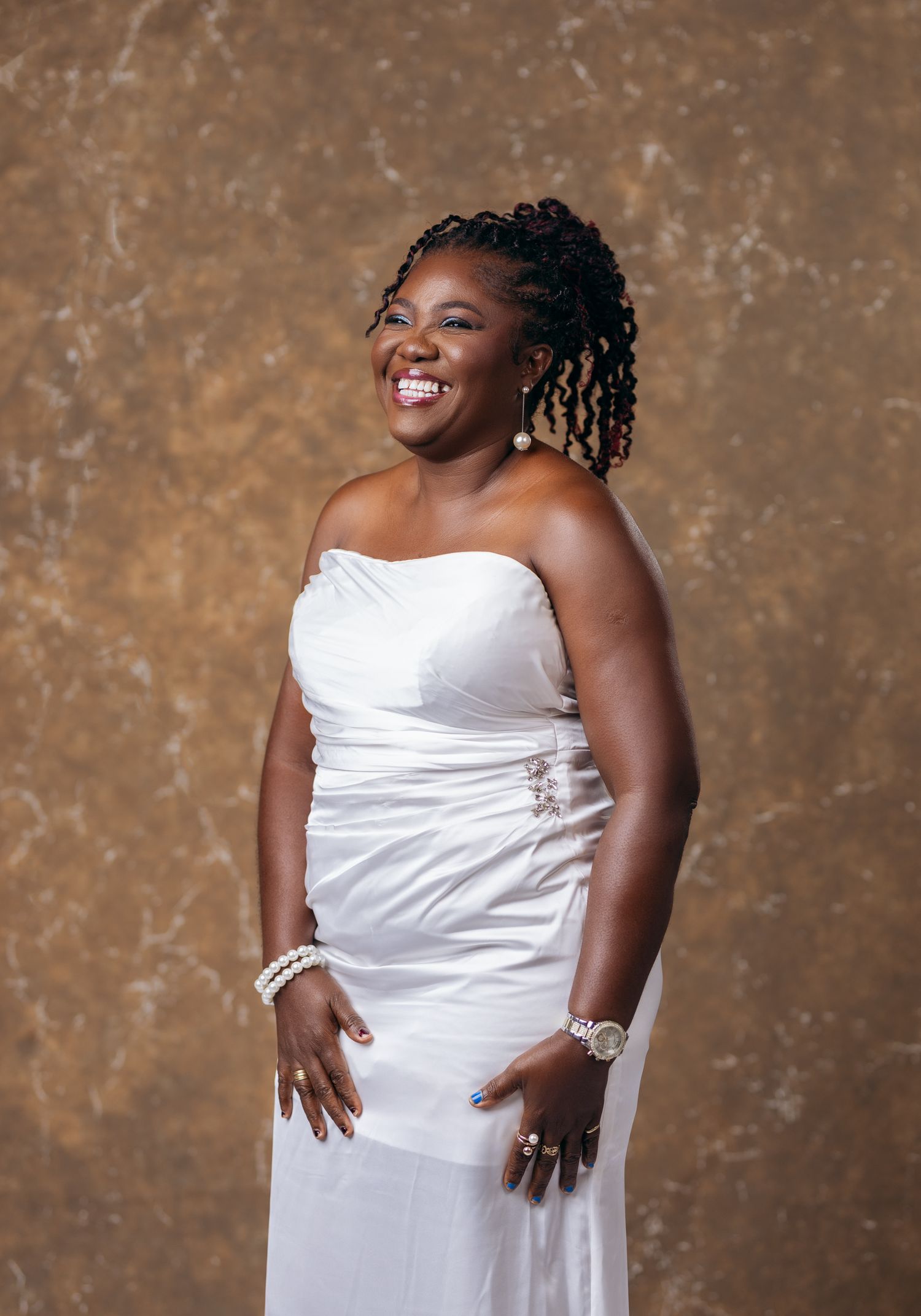 Joyful woman in white strapless gown laughing during professional portrait session.