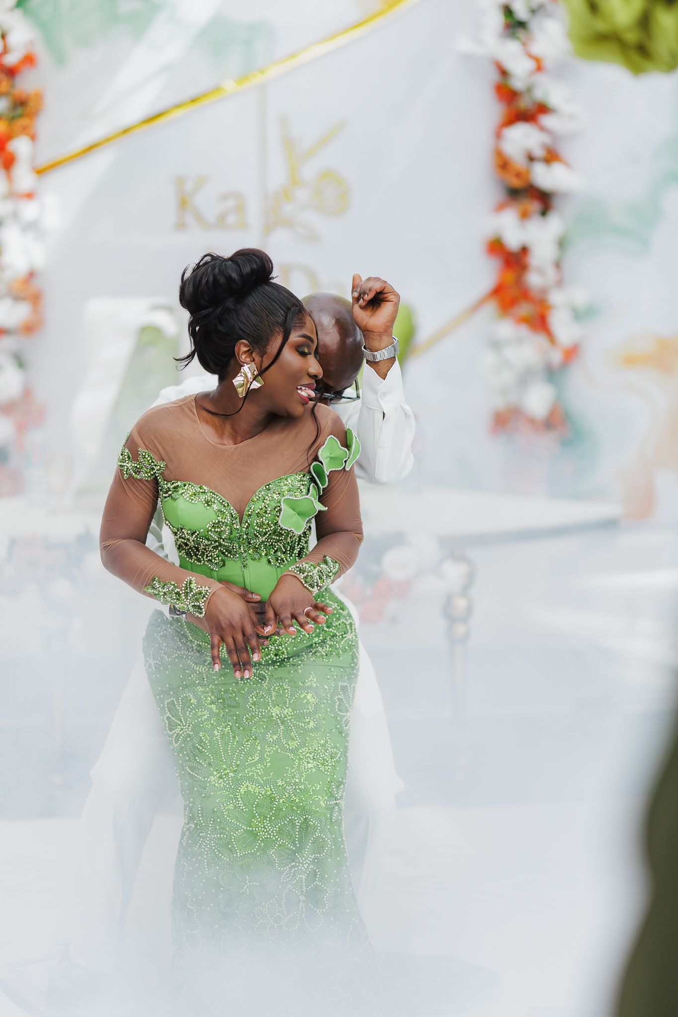 A bride in a stunning green lace mermaid gown dances with her groom amid a misty wedding reception.