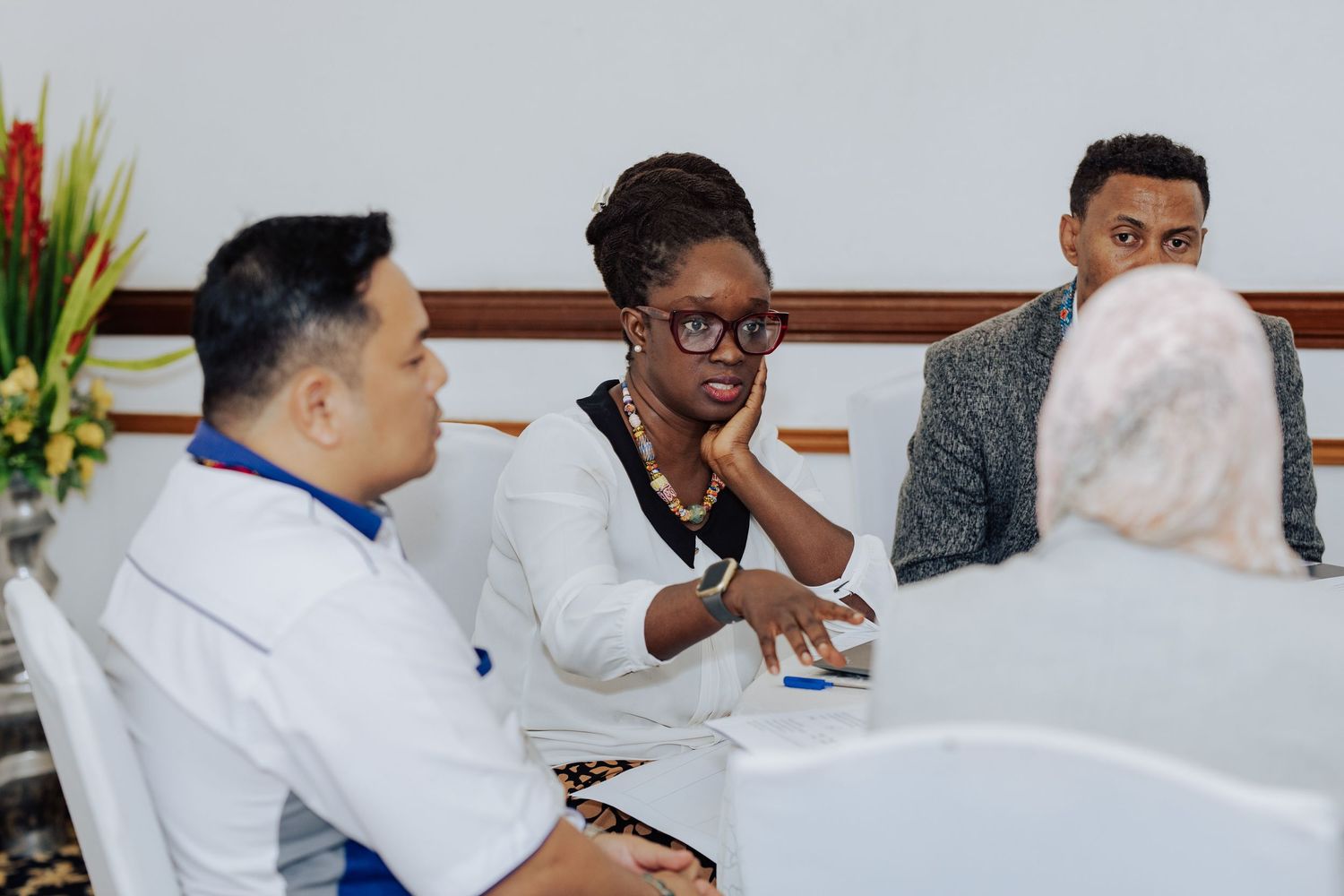 Diverse group of professionals engaged in a serious discussion at a meeting table in a bright office setting.