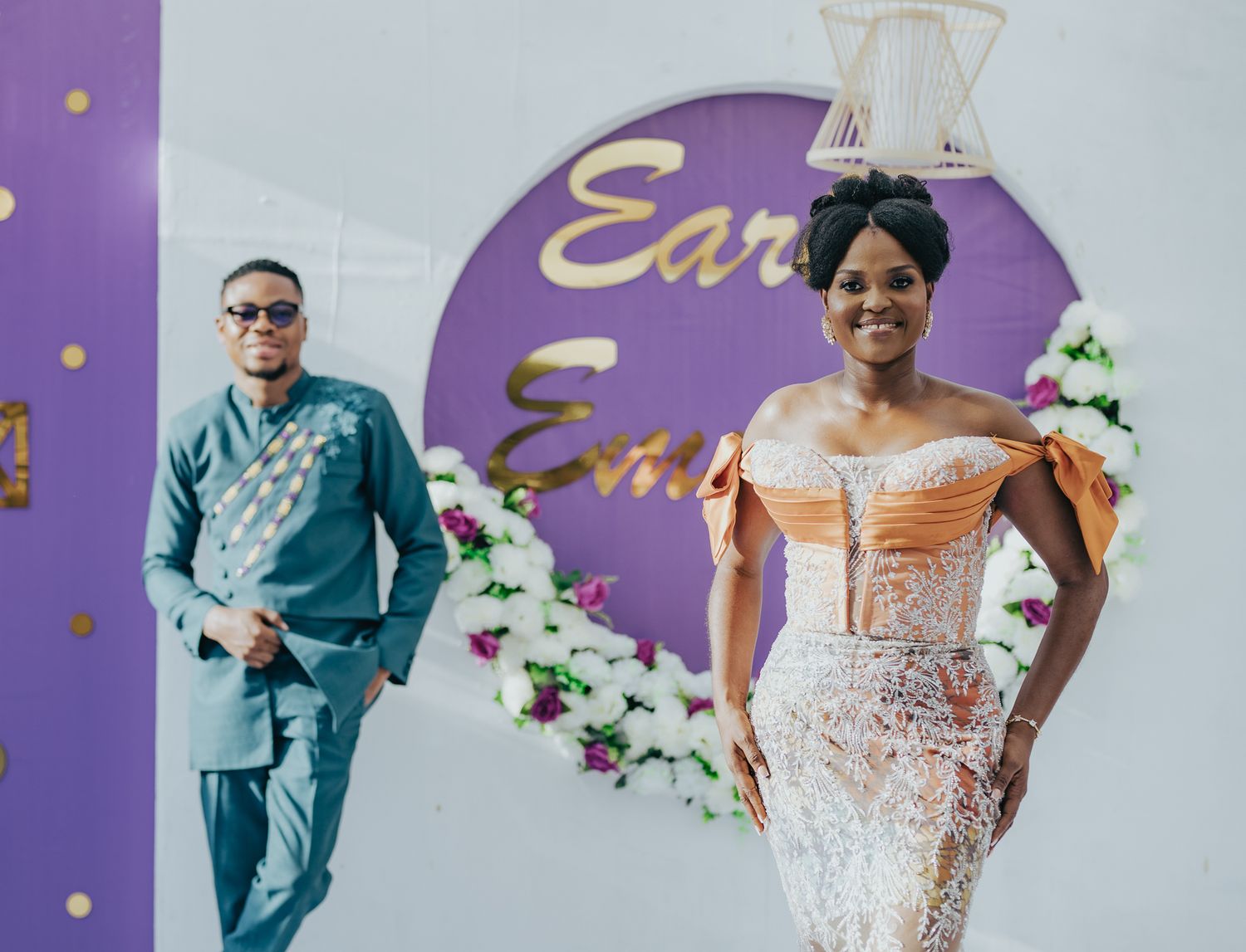Elegant couple poses before a decorative backdrop at a stylish African wedding reception.