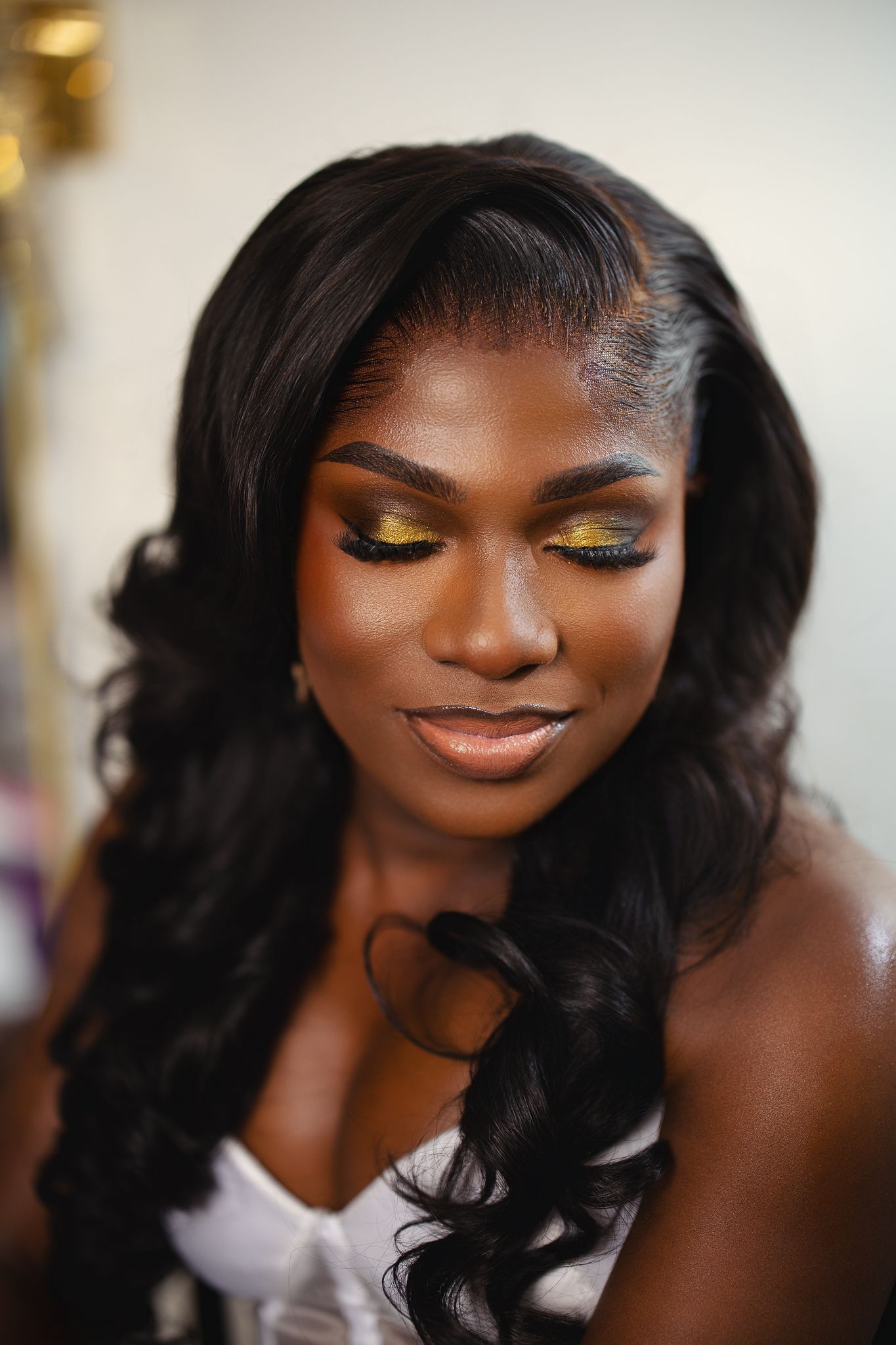 Beautiful Black bride with gold glitter eye makeup and long wavy hair.