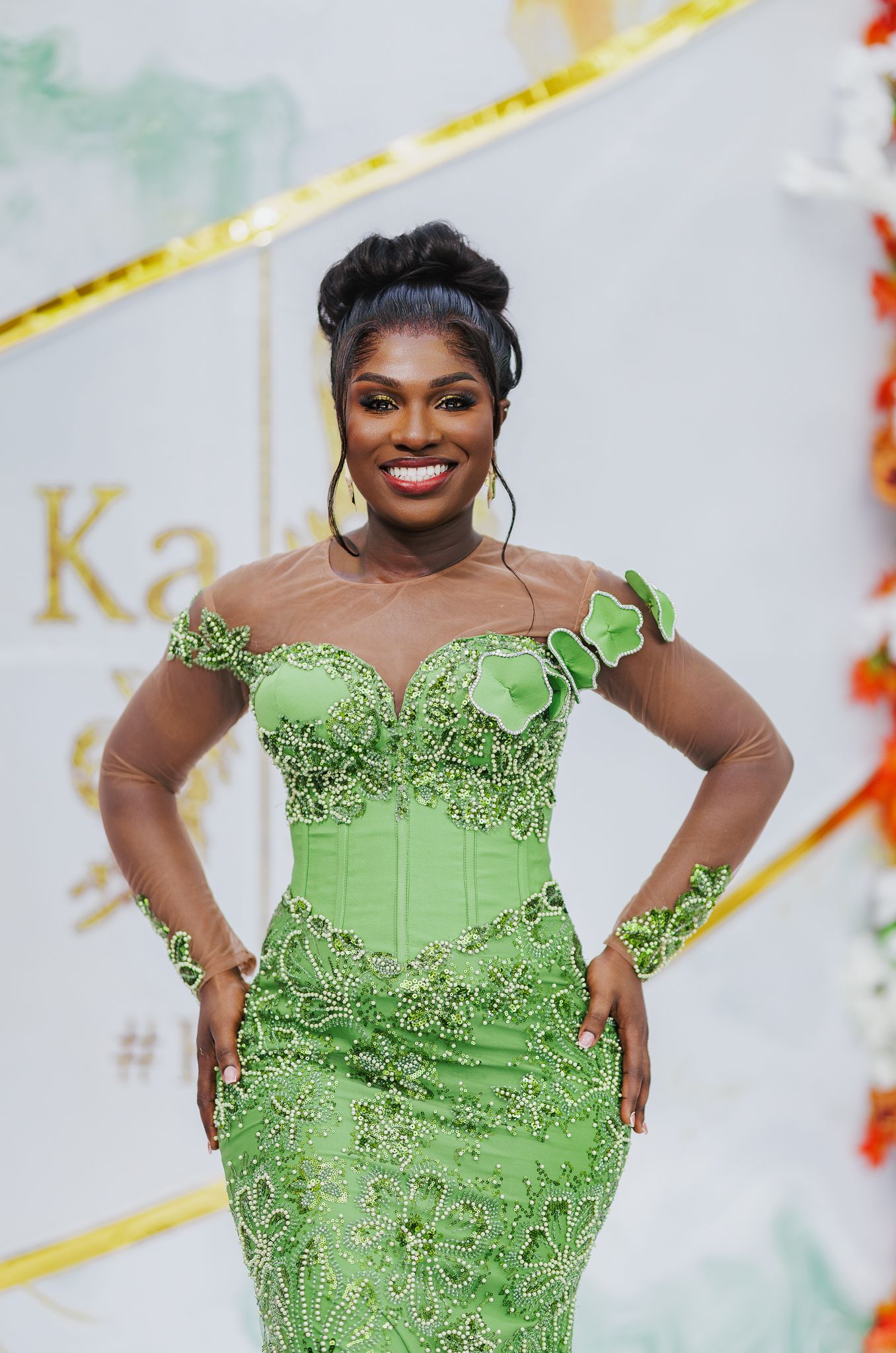 Woman in elegant green floral embroidered off-shoulder gown posing confidently at a formal event.