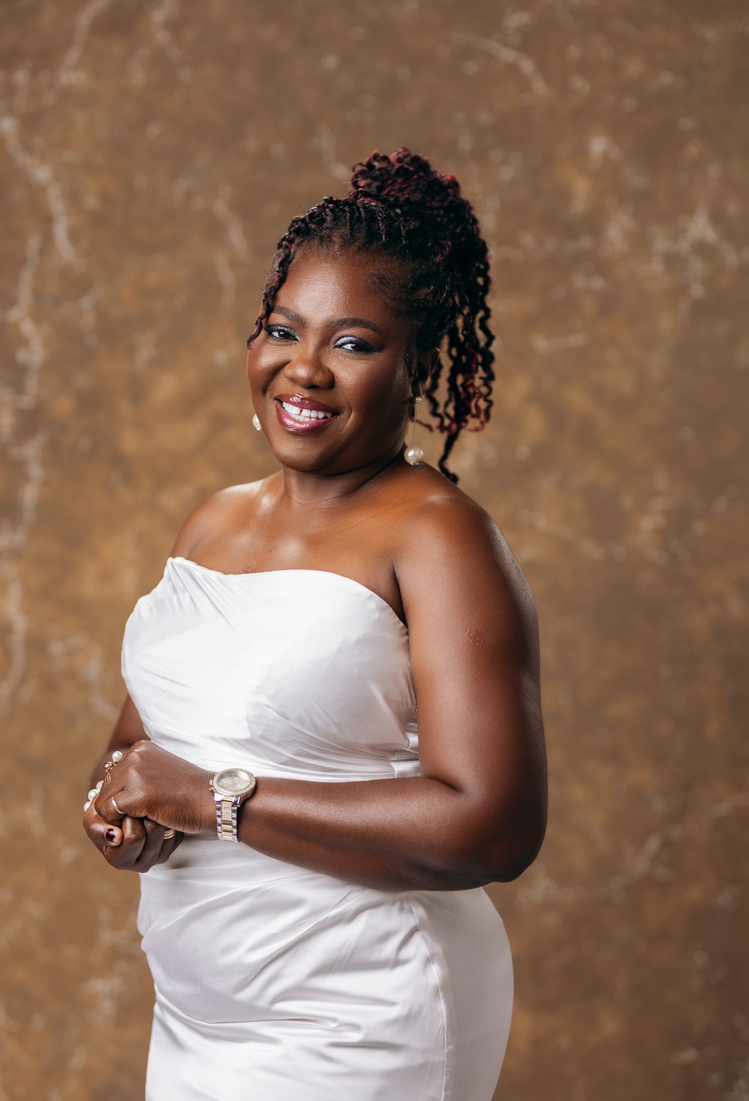 Happy woman in white strapless dress smiling warmly during elegant professional photo session.