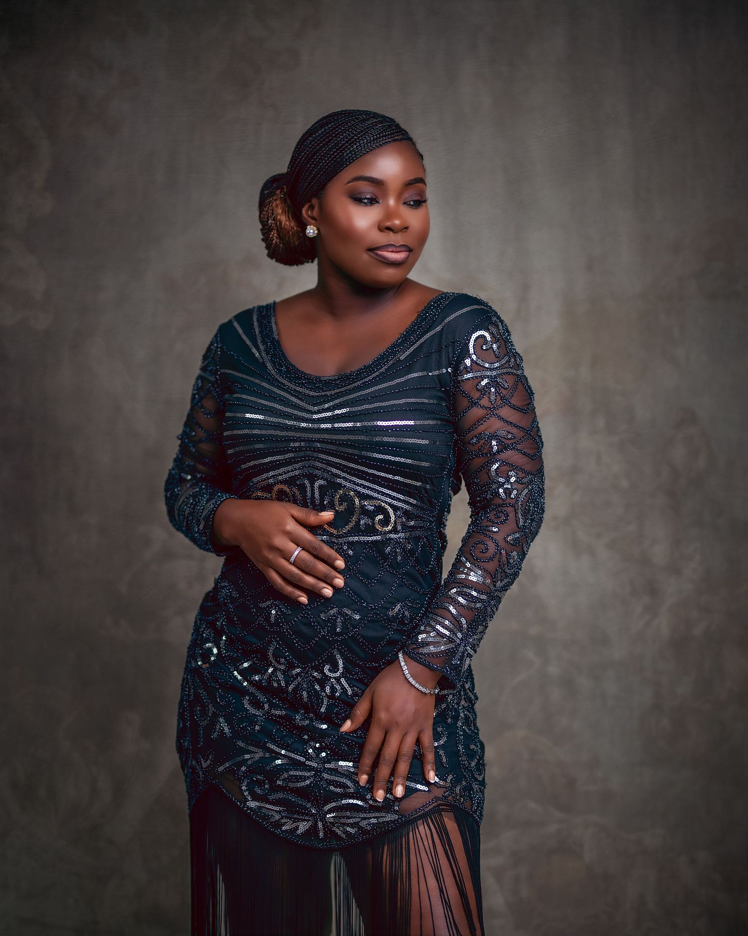 Woman in elegant dark teal sequined lace gown posing gracefully in professional studio portrait photography.