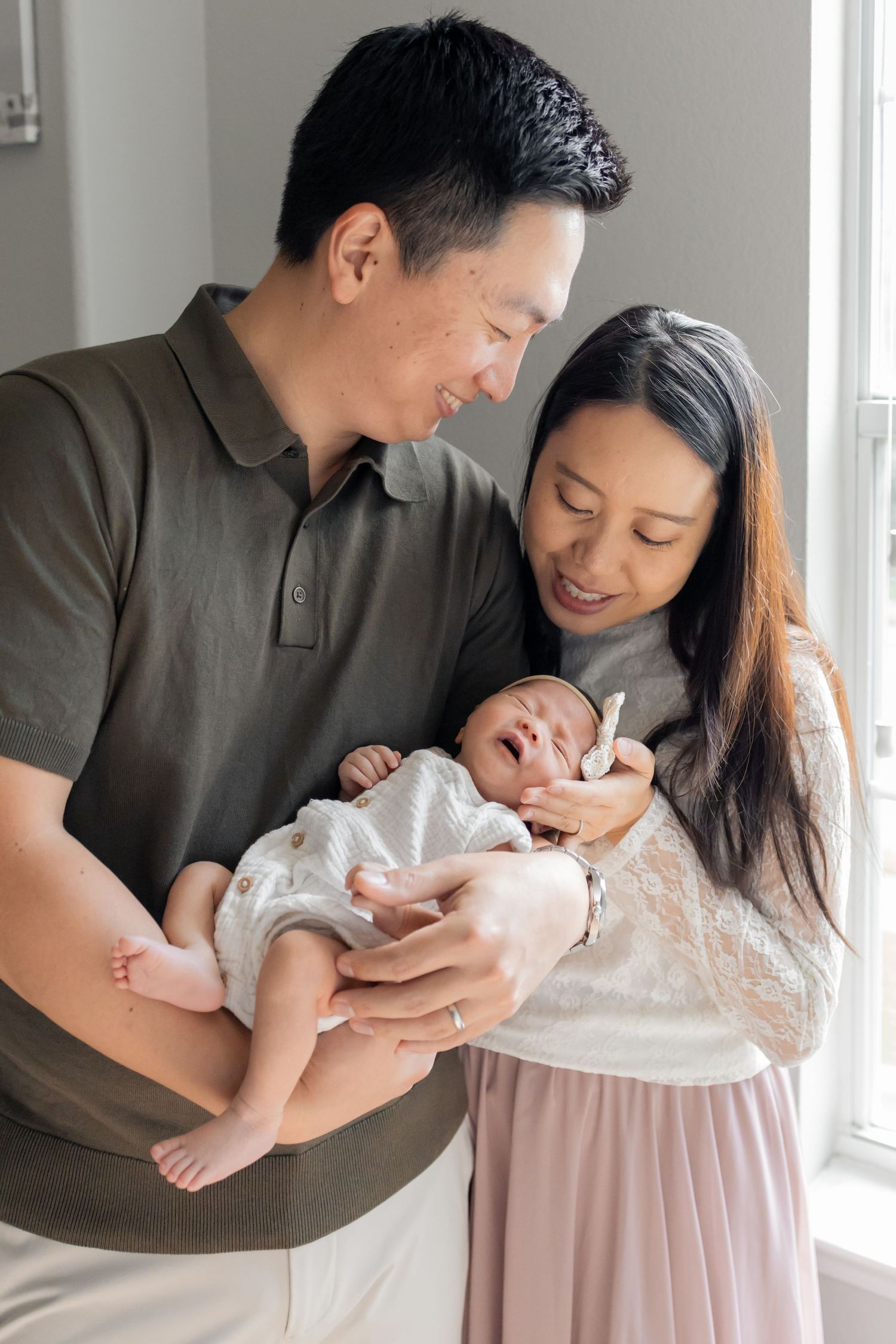 Parents holding newborn baby at home during a natural light lifestyle newborn session