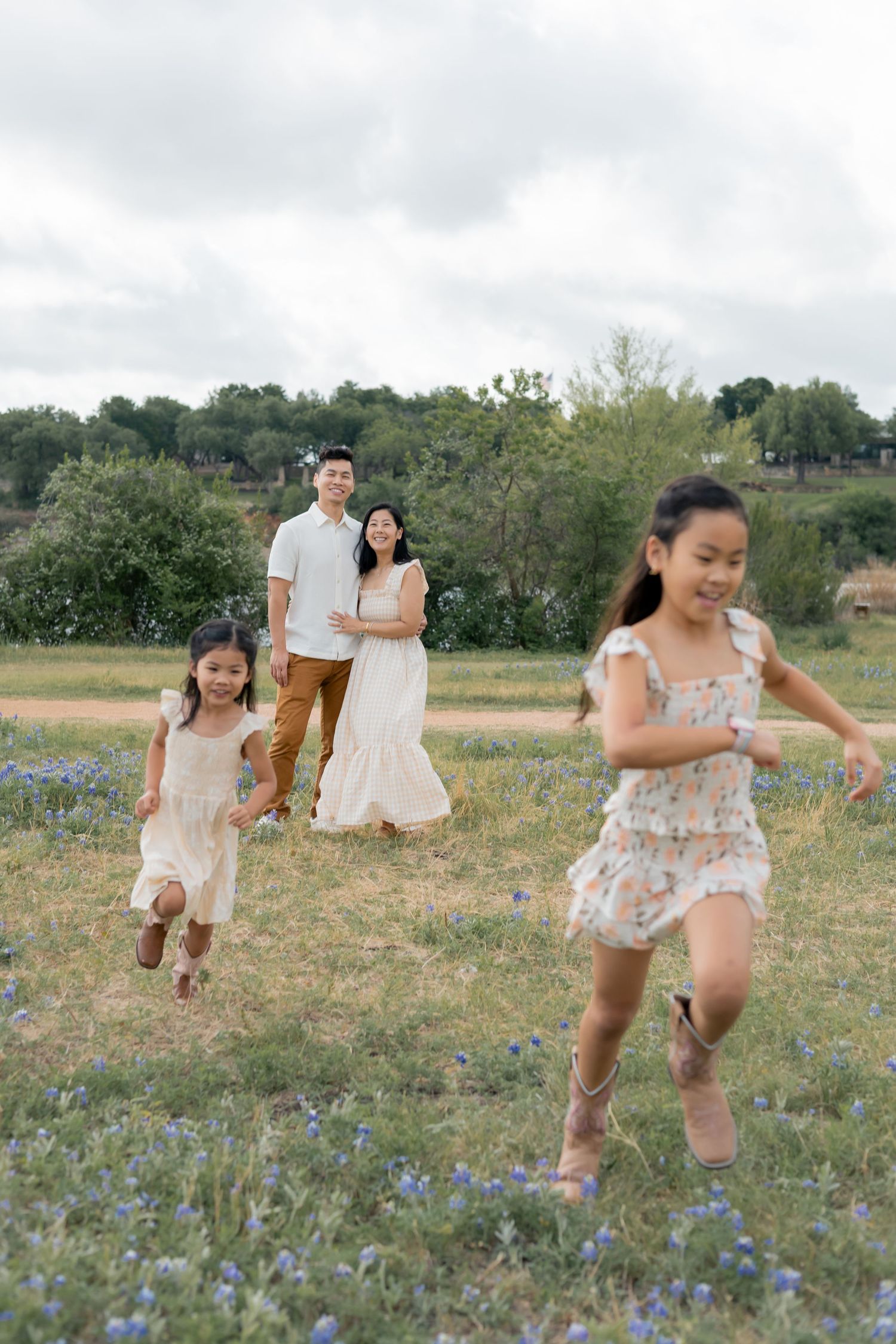 Children running away from their parents as they gaze towards them in a grassy field during a family lifestyle session
