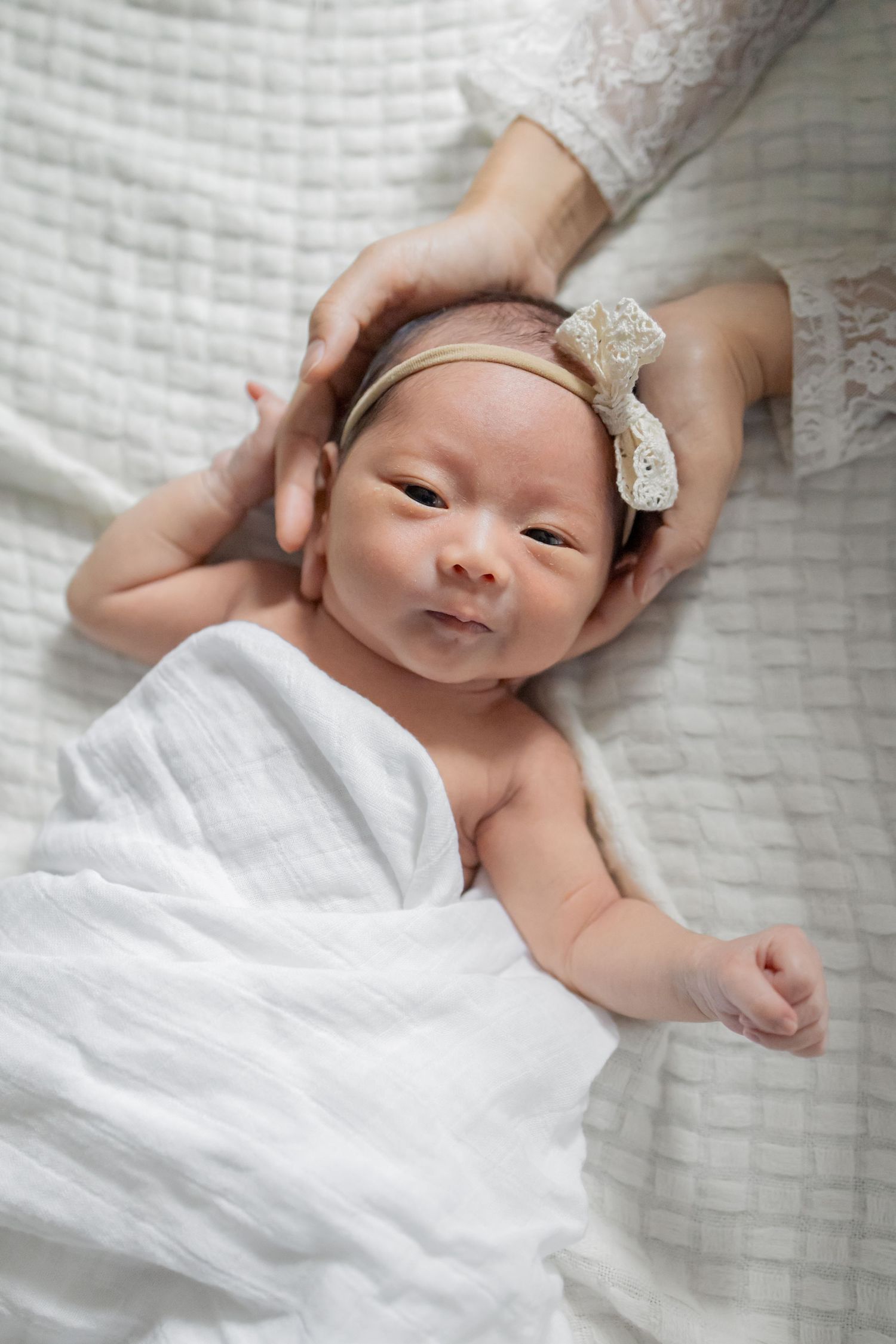 Newborn baby laying on bed peacefully during a natural light lifestyle newborn session