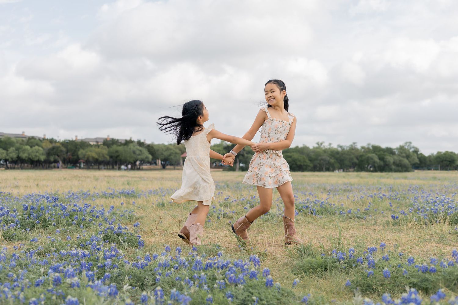 Sisters running around holding hands and smiling at one another during a lifestyle family session