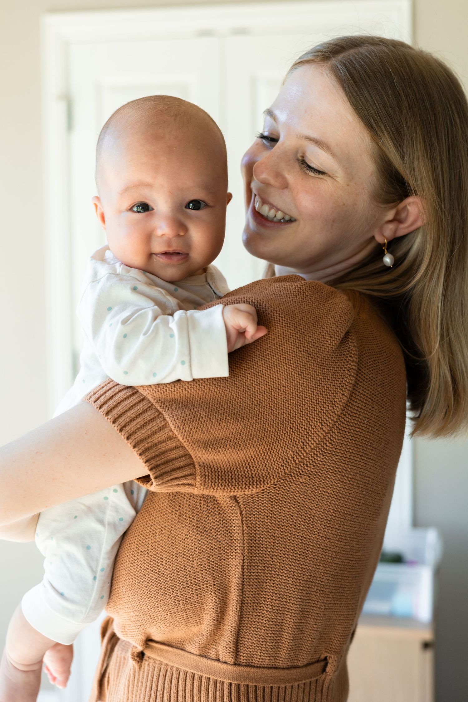 Mother holding her son and smiling at him during a newborn lifestyle session
