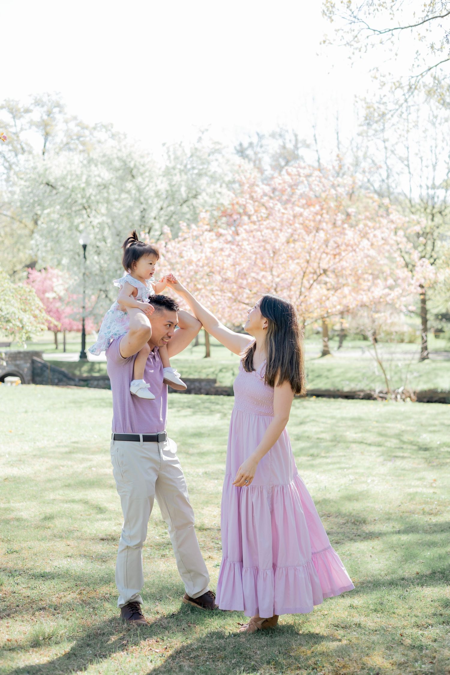 Family holding hands and dancing together during a lifestyle family session outdoors in a park