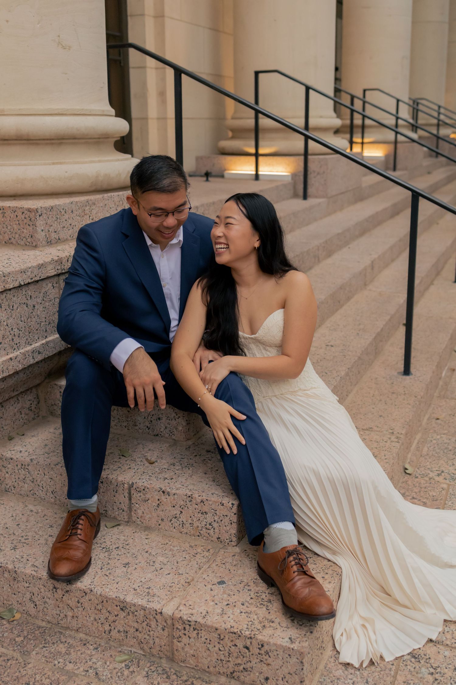Couple sitting and laughing together in downtown Austin during a sunrise engagement session