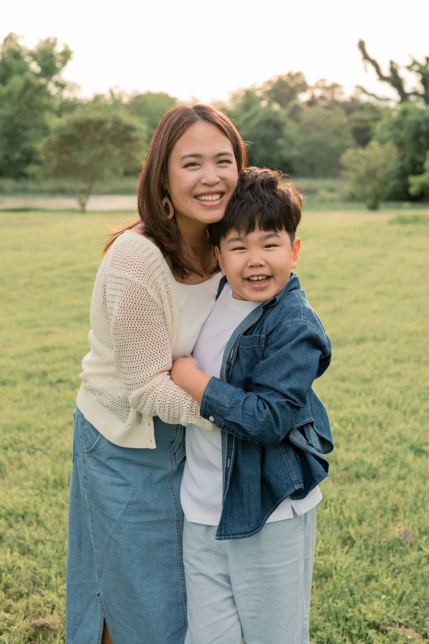 Mother and son holding one another and smiling together at a sunset lifestyle family session