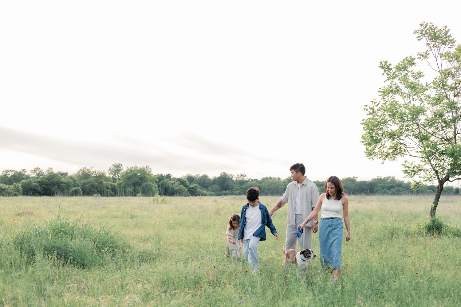 Family walking in a grassy field during a sunset lifestyle family session