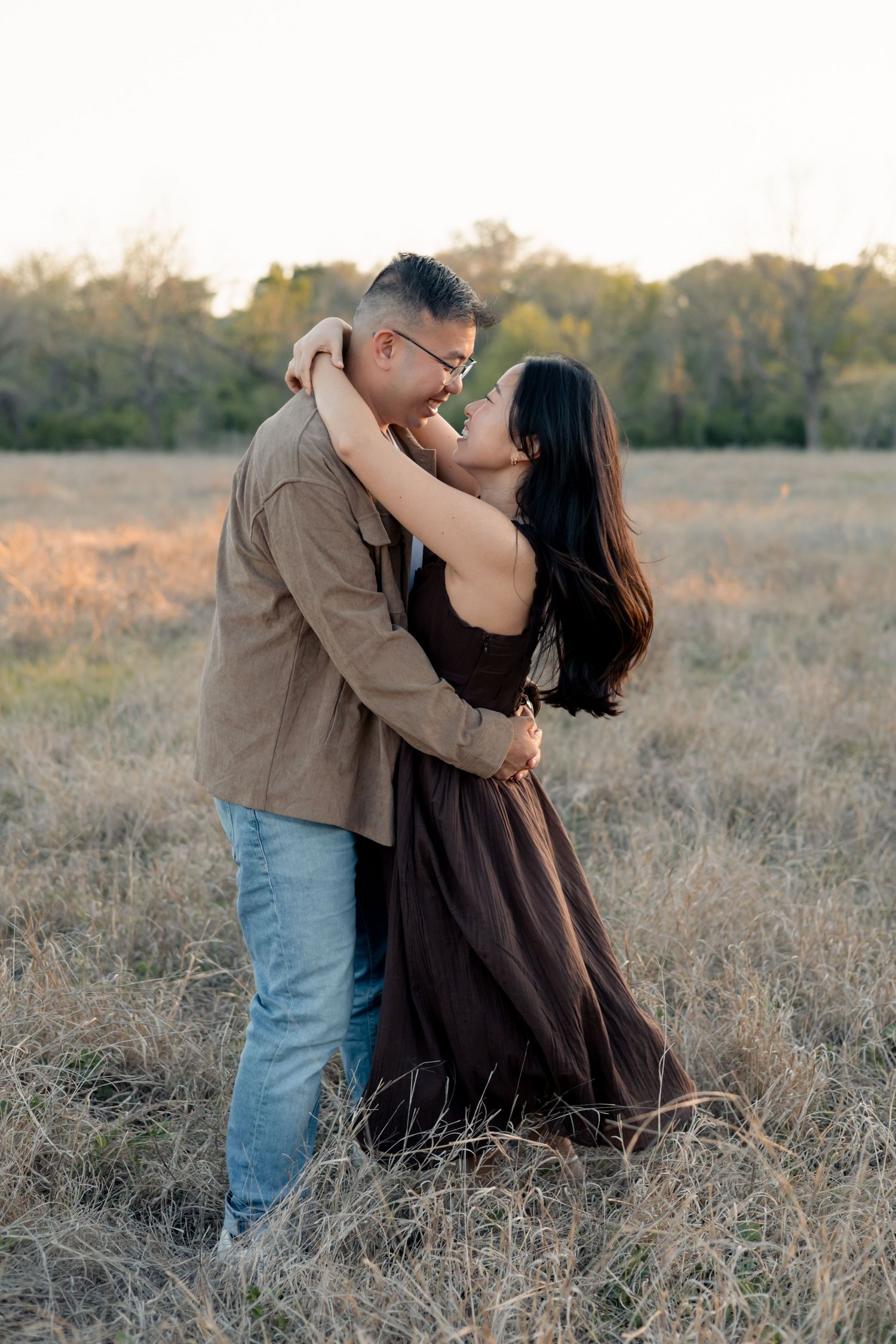 Couple embracing one another in a field in Central Texas during a sunset engagement session
