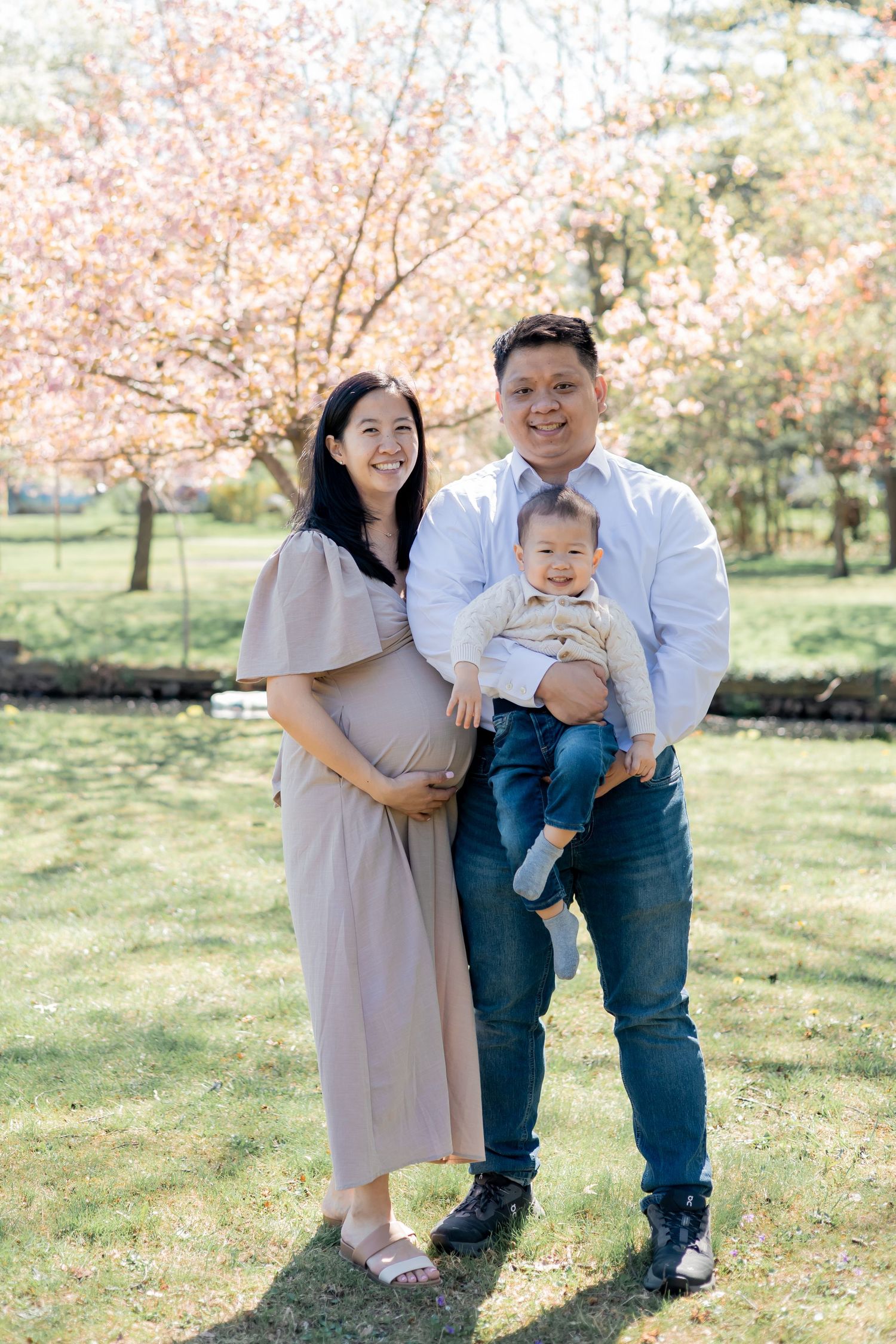 Pregnant Couple expecting their second baby holding their first child in a lifestyle family session outdoors