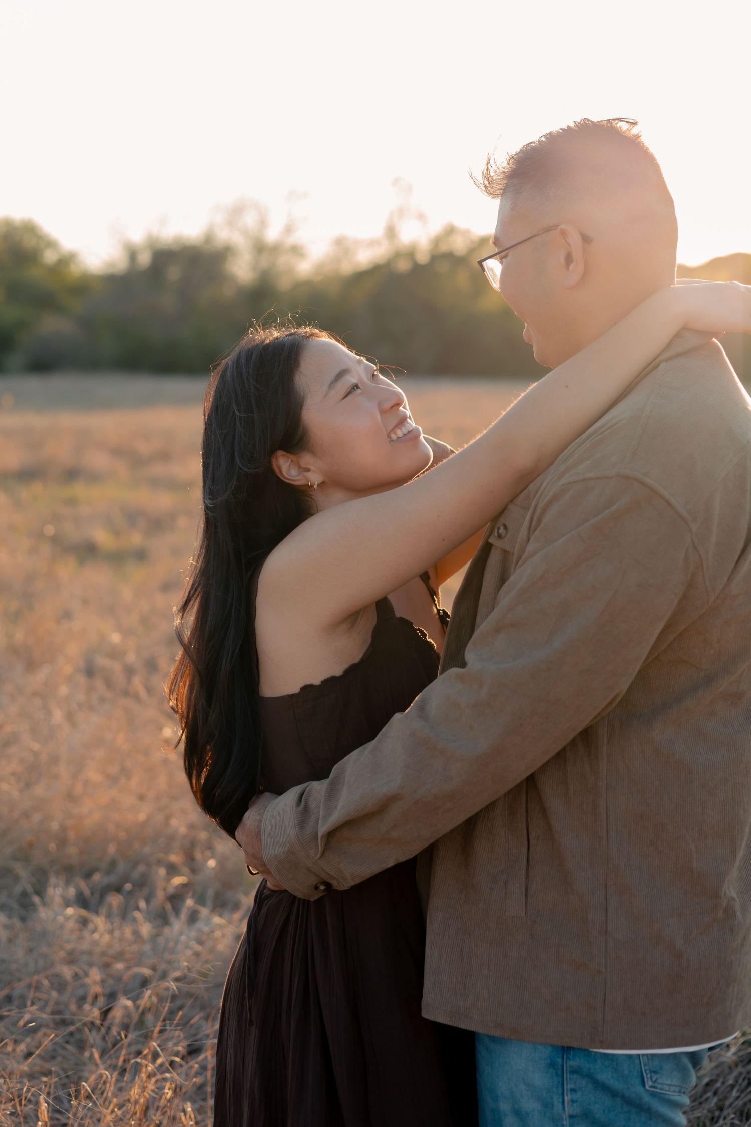 Couple embracing one another in a field in Central Texas during a sunset engagement session