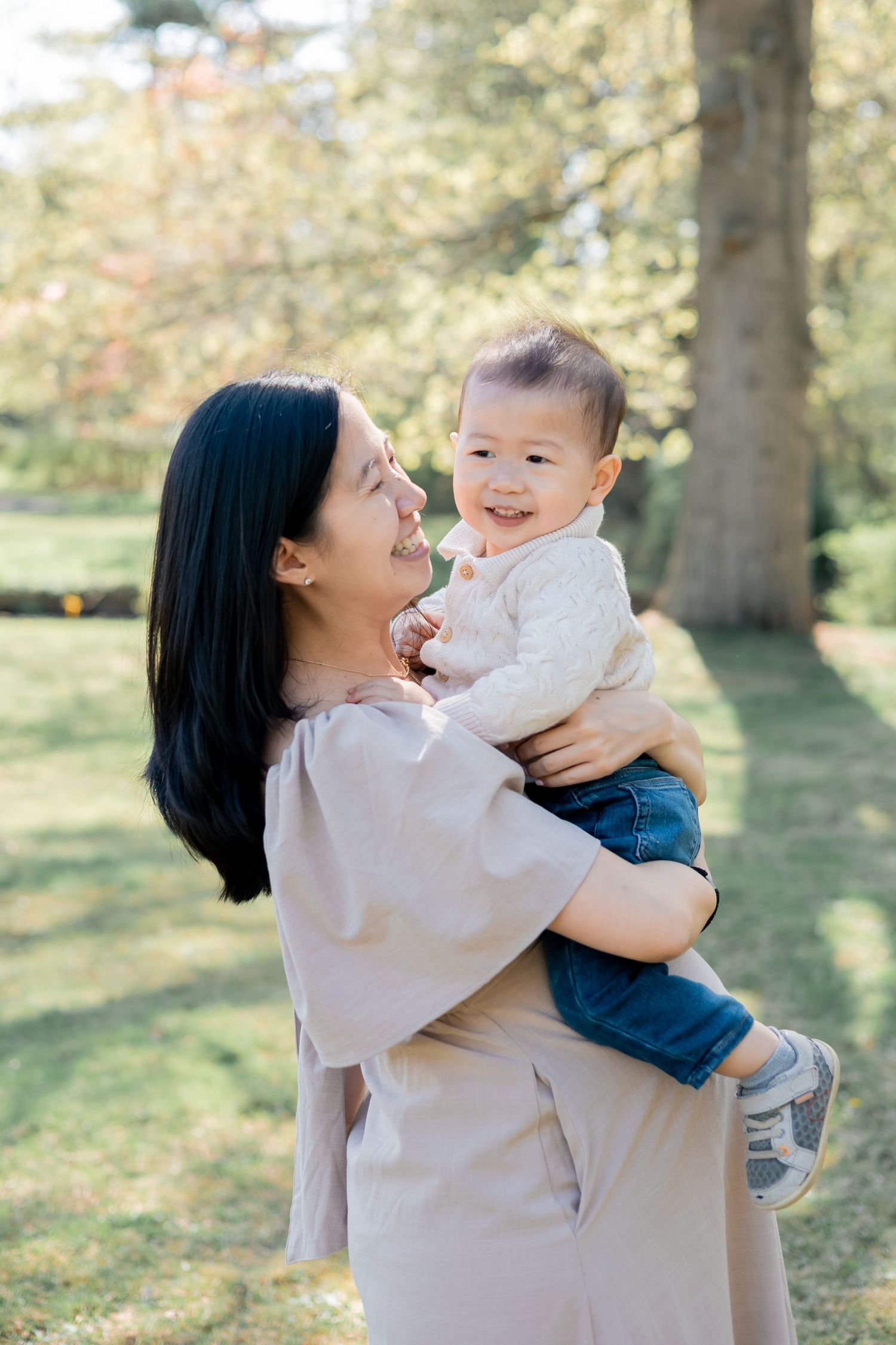 Pregnant mother holding her son in a family session outdoors in a park