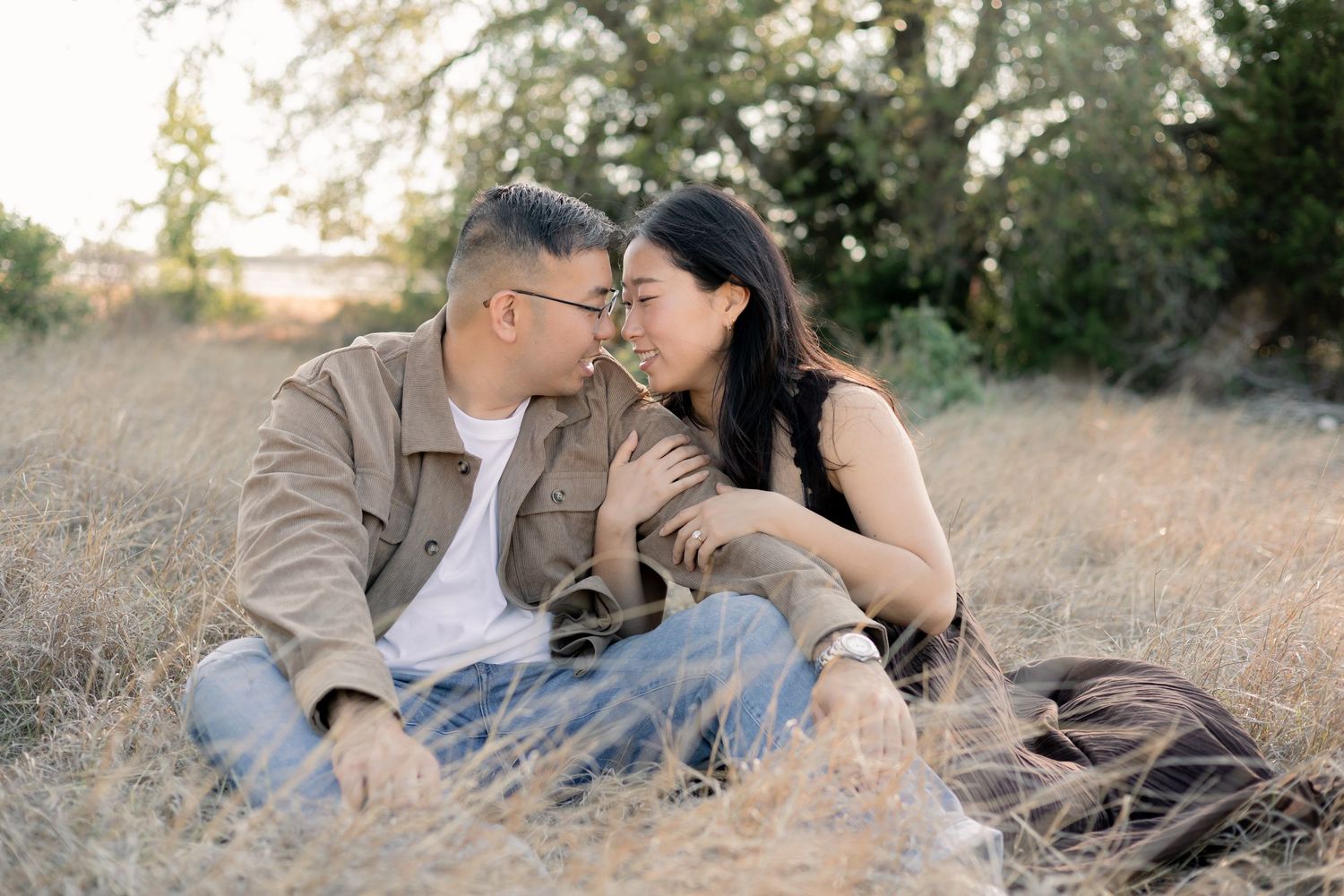 Couple embracing one another in a field in Central Texas during a sunset engagement session