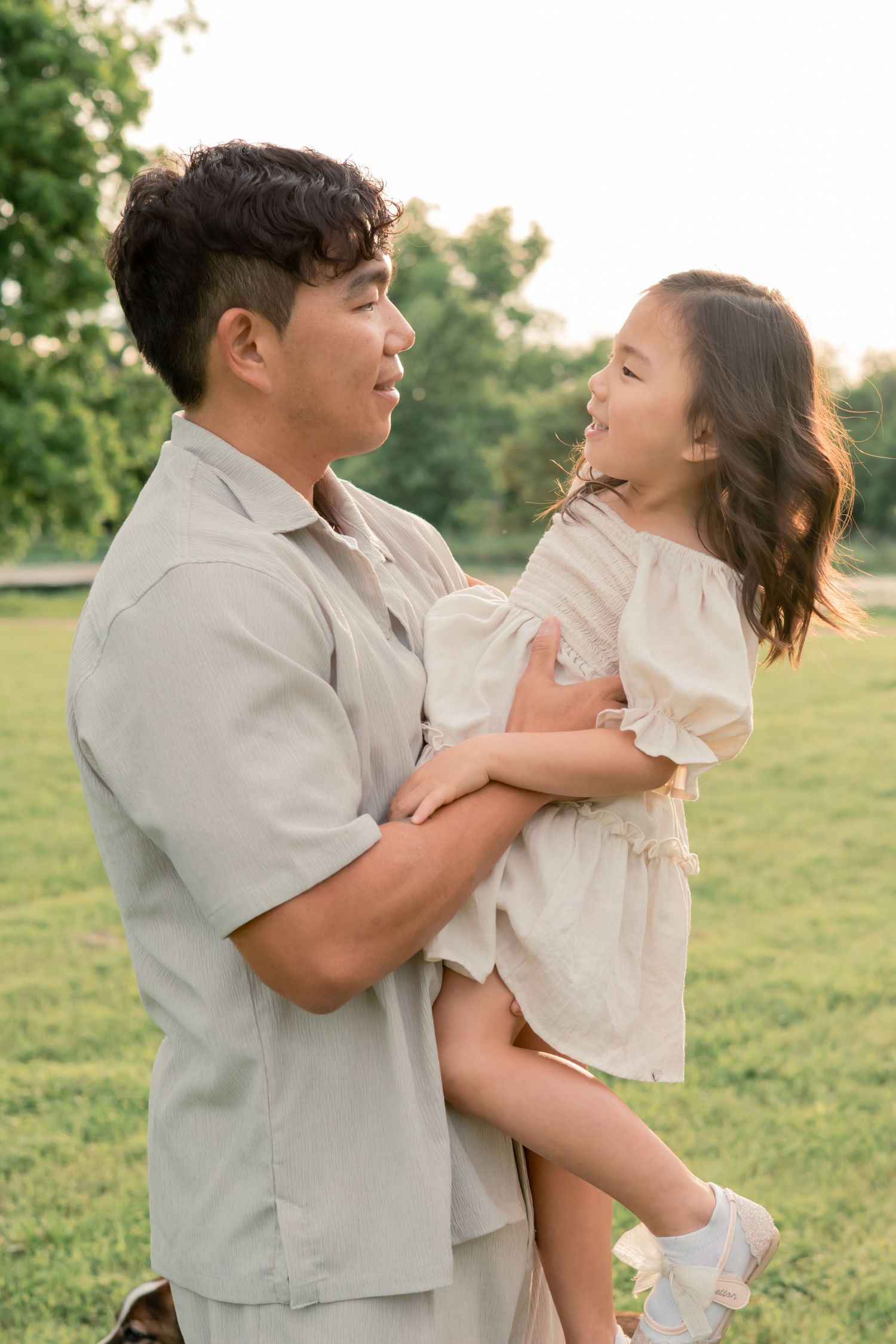Father and daughter looking at one another and smiling together at a sunset lifestyle family session